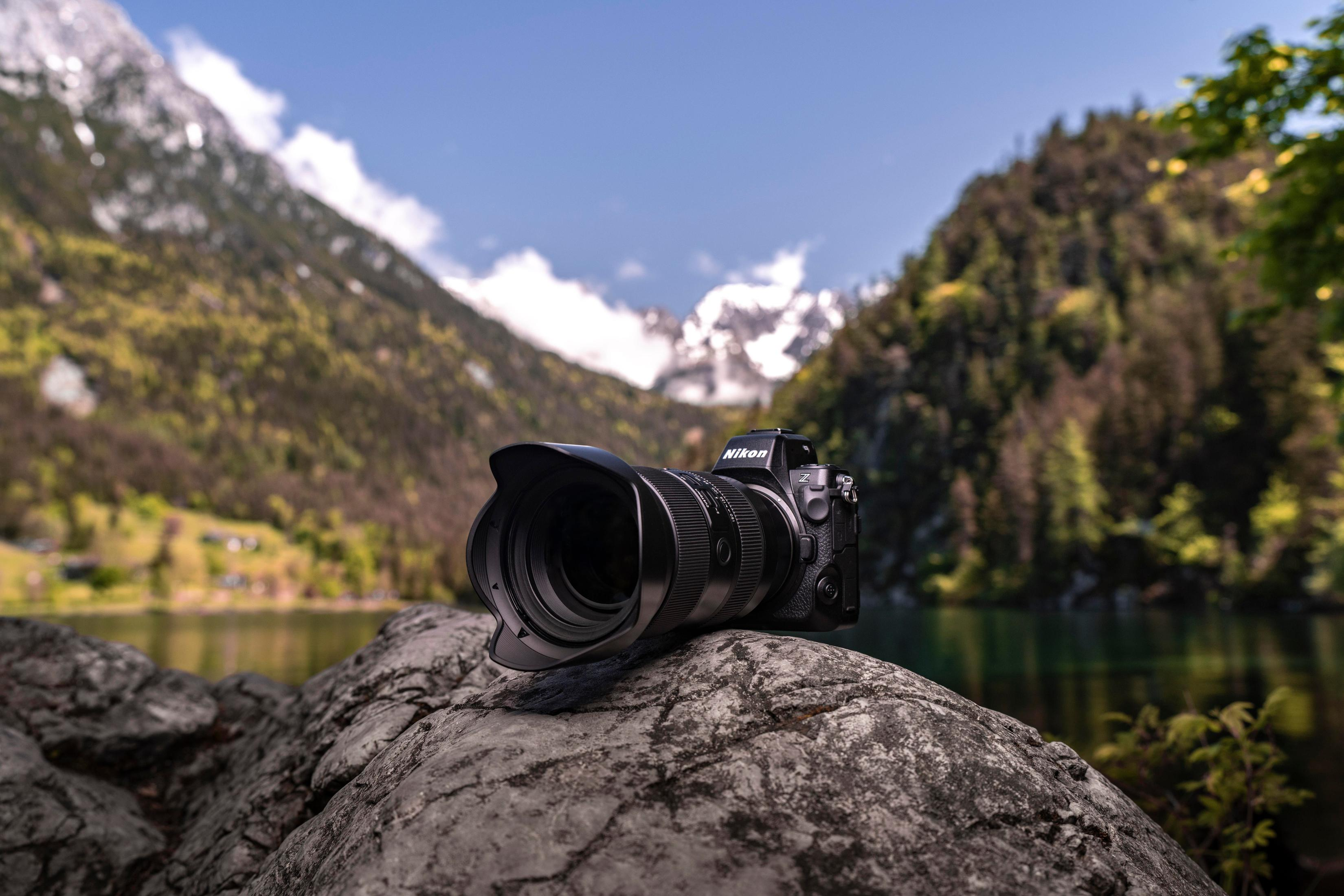 Aparat na skale z jeziorem i górami w tle.