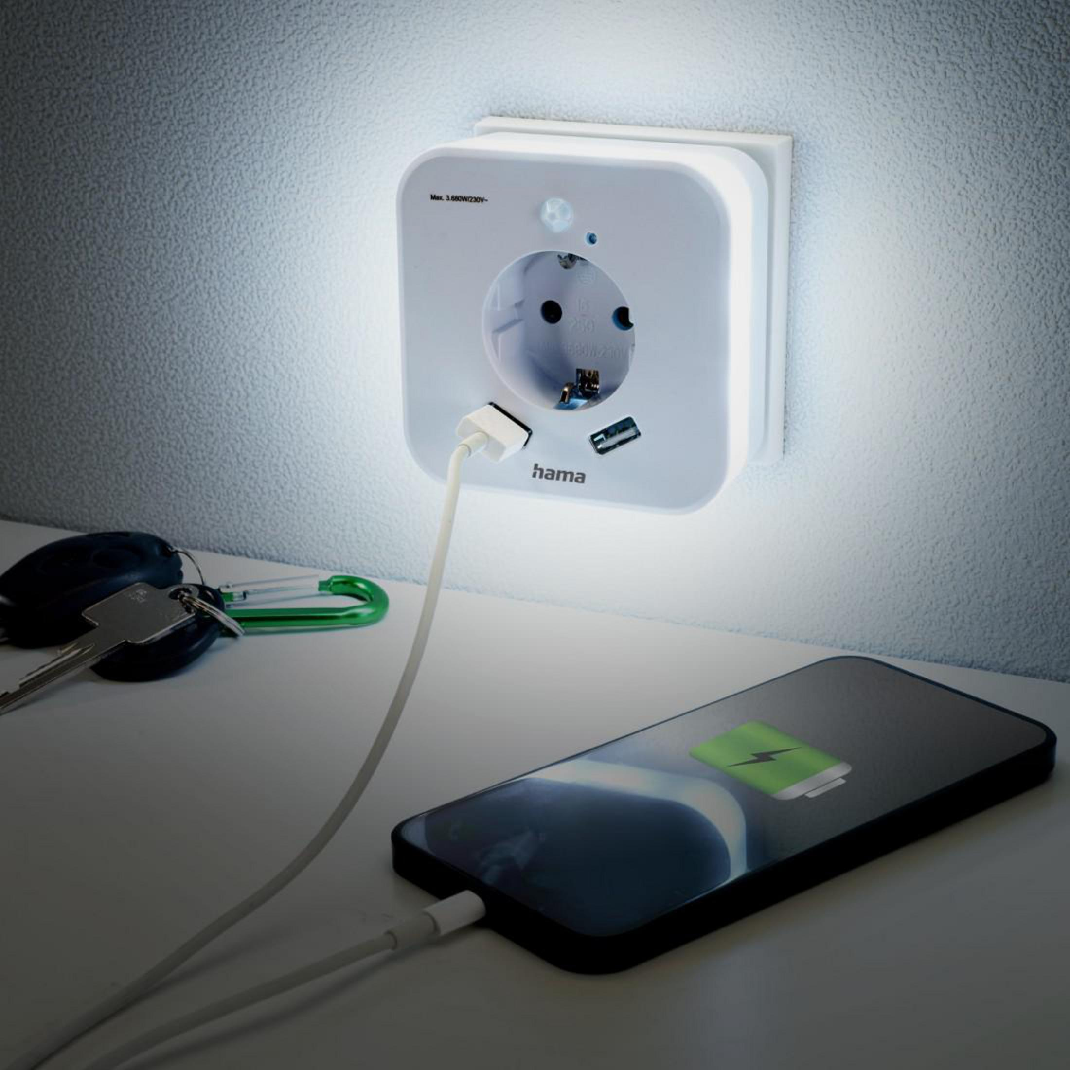 Ein Smartphone, das neben einer Steckdose mit USB-Ladegerät aufgeladen wird. Die Steckdose ist weiß.