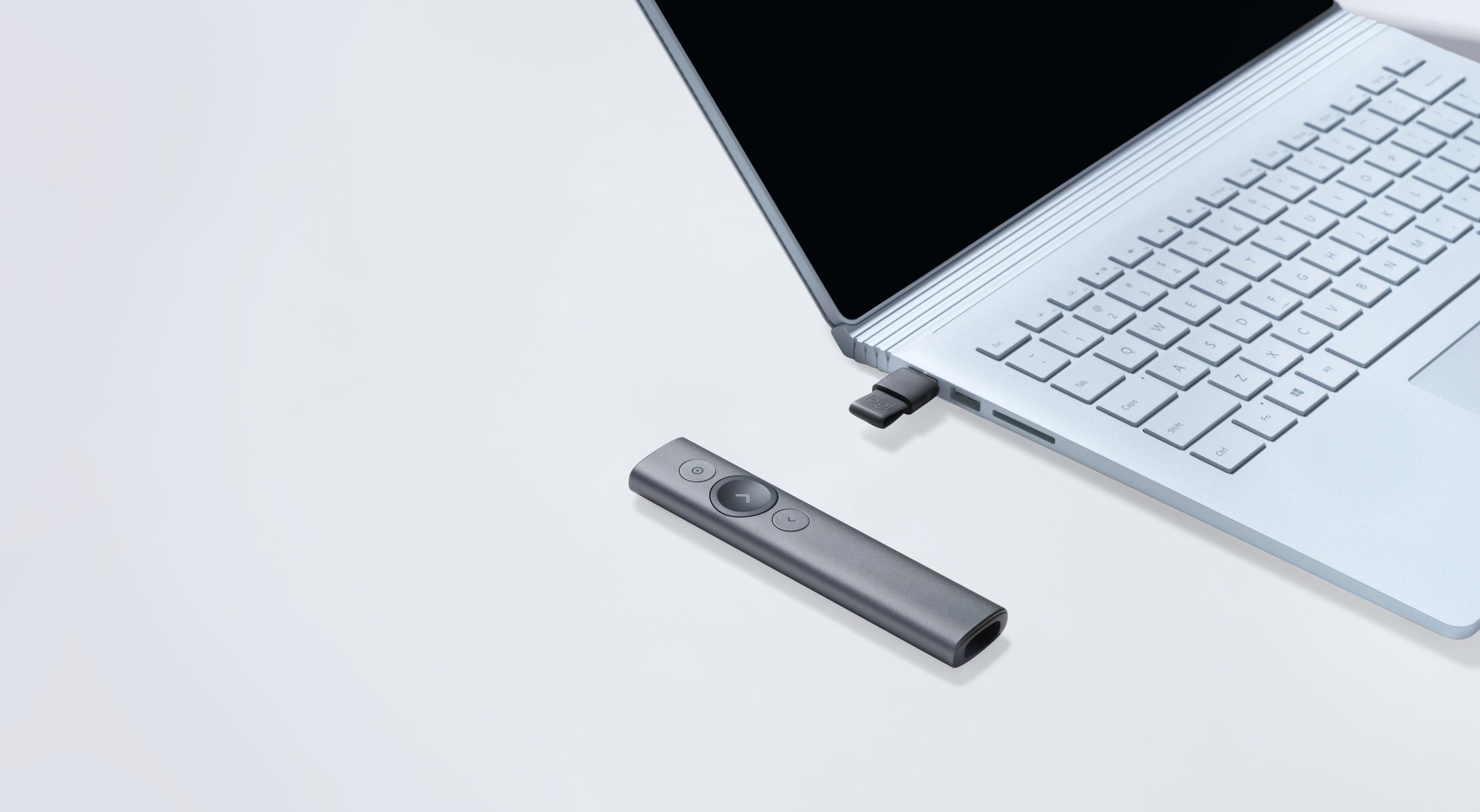 Szary pilot Logitech Spotlight obok laptopa z wpiętym kluczem USB-C.