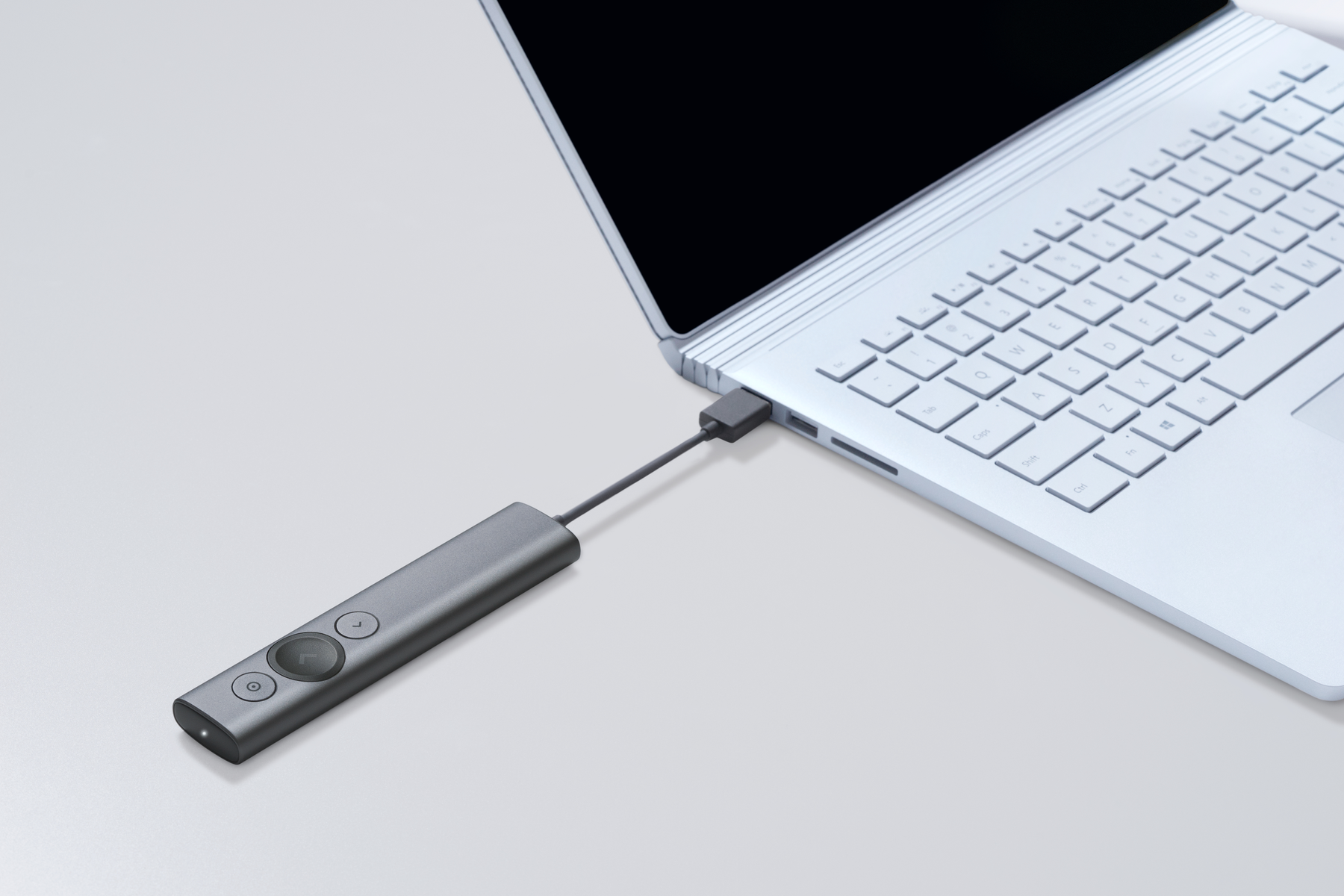 Szary pilot Logitech Spotlight podłączony do laptopa kablem USB-C.
