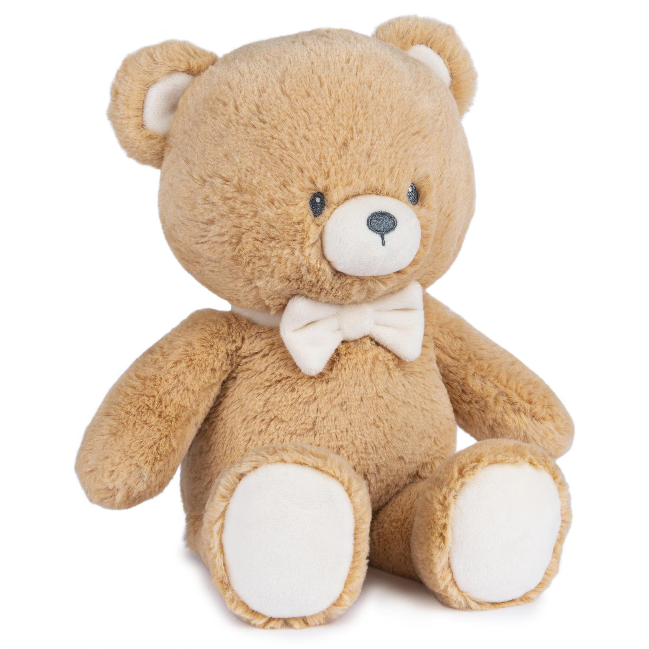 Ein braunes Teddybär-Spielzeug mit weißer Fliege, sitzt auf einer weißen Oberfläche.