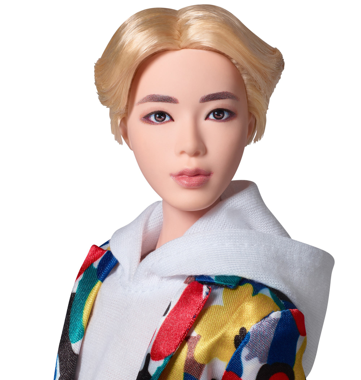 Eine Puppe einer Person mit blonden Haaren, die einen weißen Kapuzenpullover und eine bunte Jacke trägt.