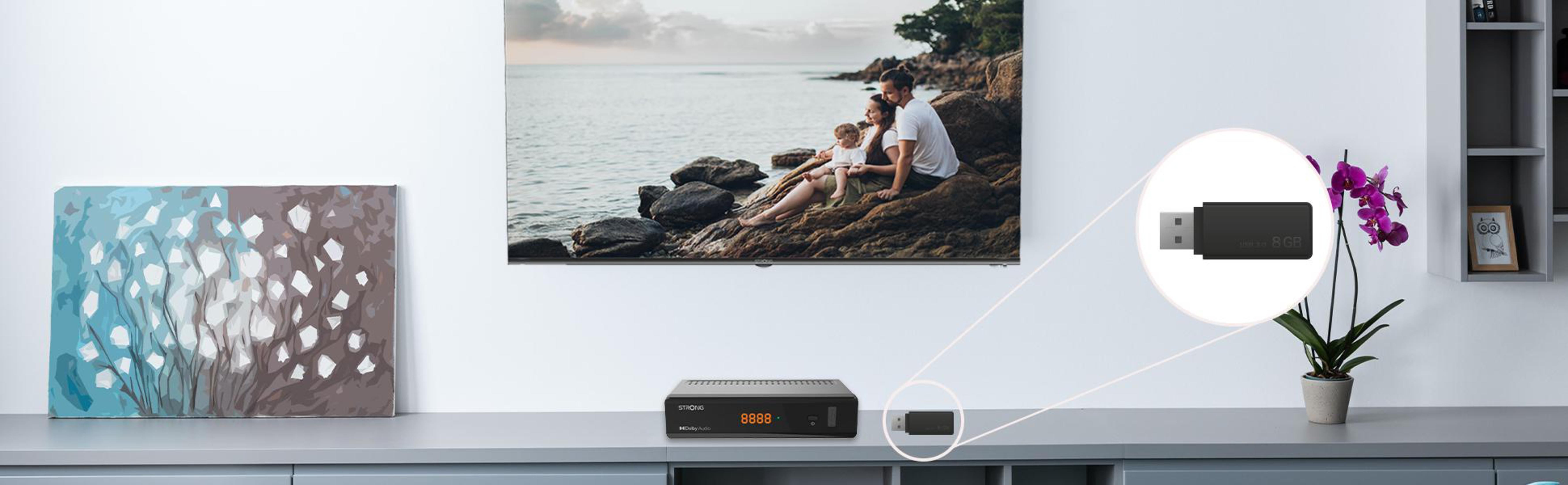 Ein Fernseher, eine Set-Top-Box und ein USB-Dongle stehen auf einem Schrank.