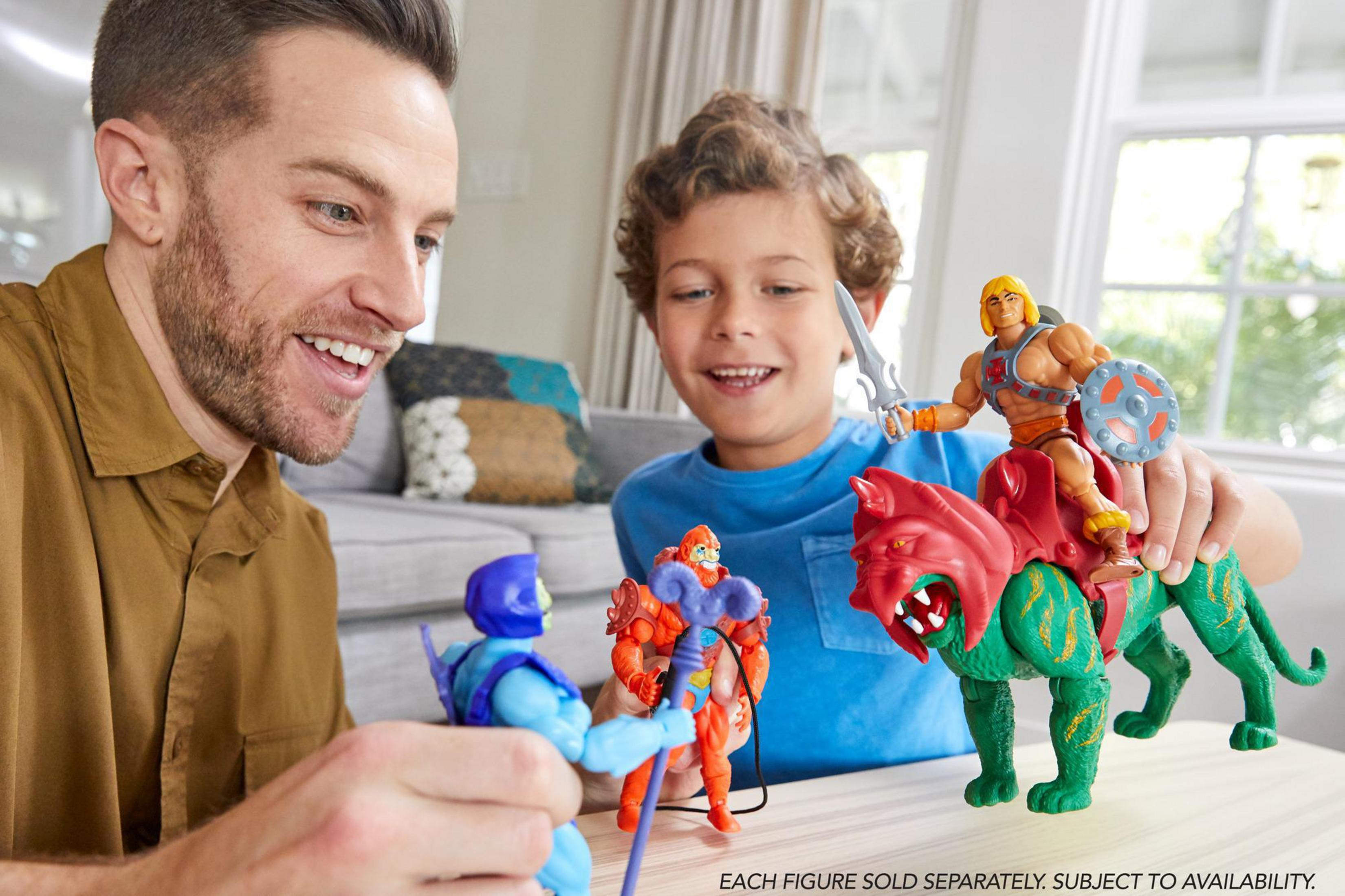 Zwei Männer und ein Junge spielen mit He-Man-Figuren, einer reitet auf Battle Cat.