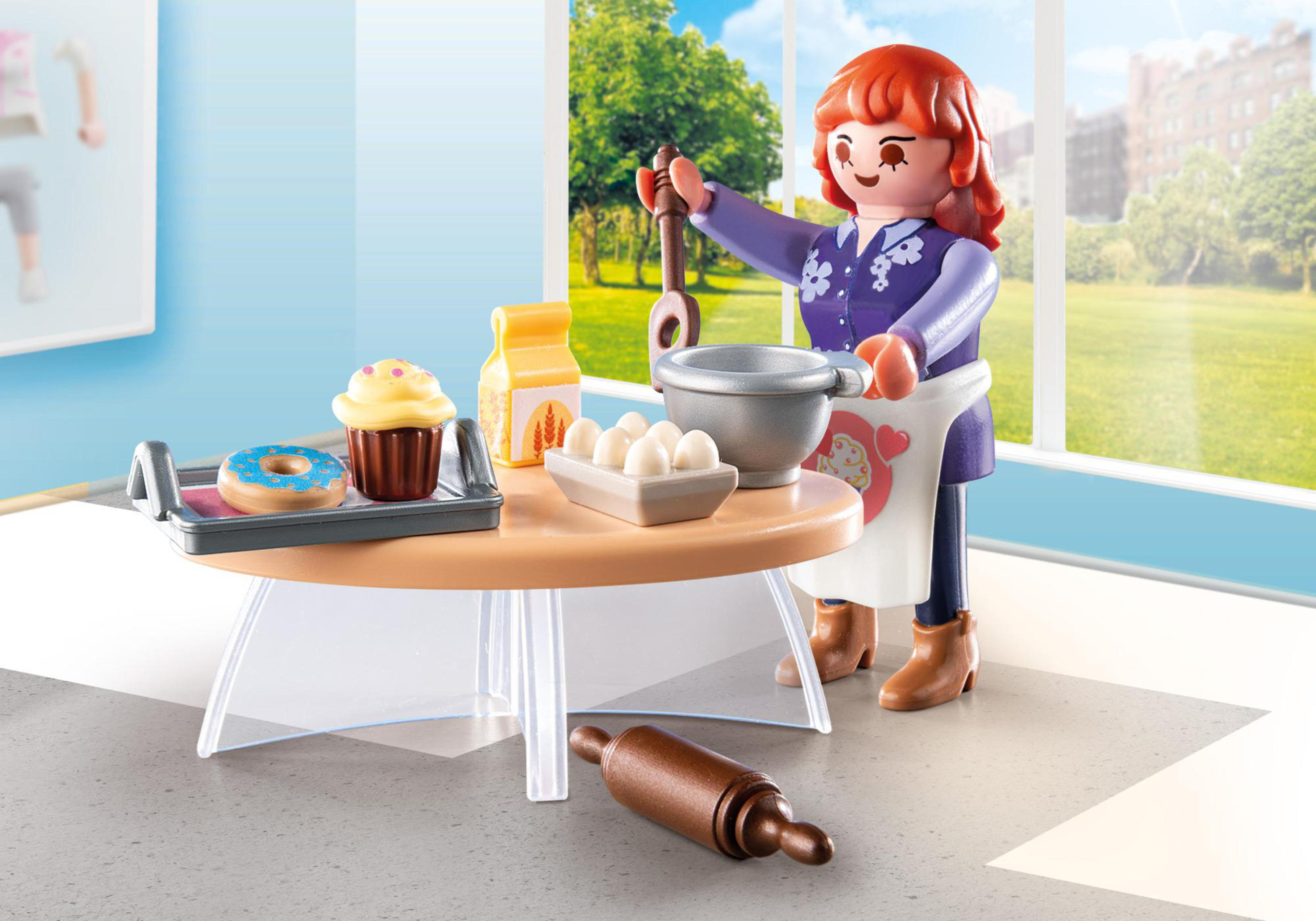 Eine Playmobil-Figur backt mit Zutaten auf einem Tisch, darunter ein Cupcake und Eier.