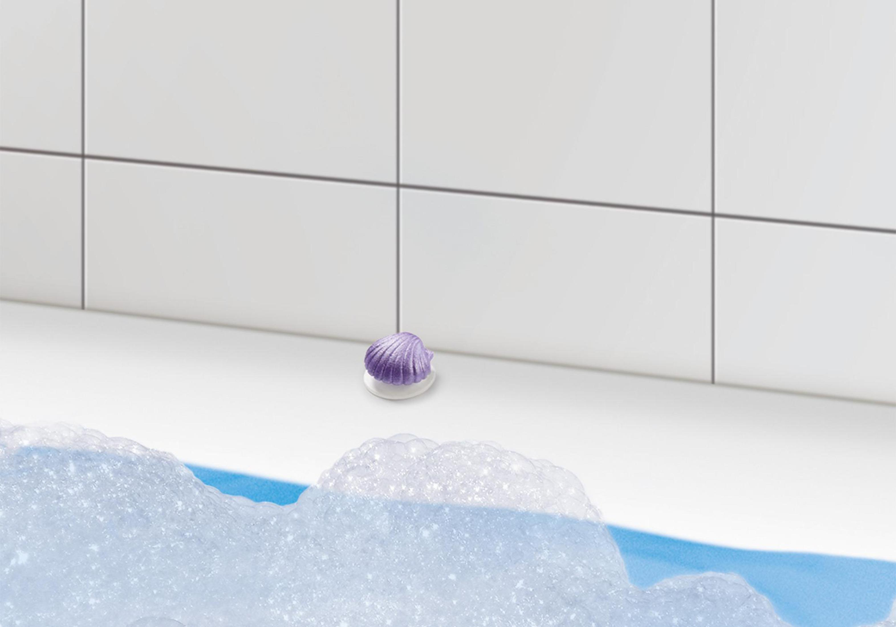 Lila muschelförmige Badekugel auf weißer Oberfläche, umgeben von Blasen.