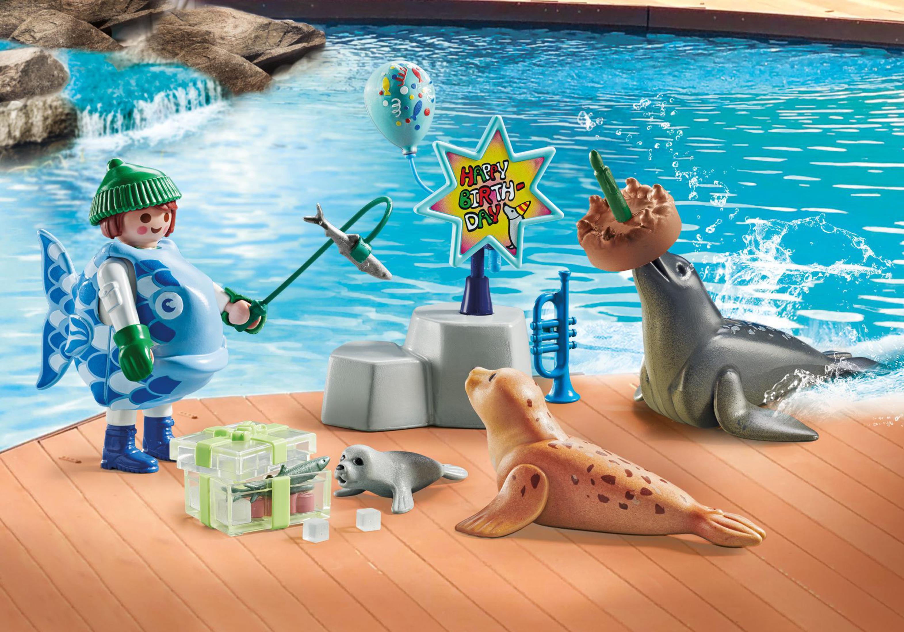 Playmobil-Szene: Fischfigur, Robben, Geburtstagskuchen und eine Bühne mit Wasser im Hintergrund.
