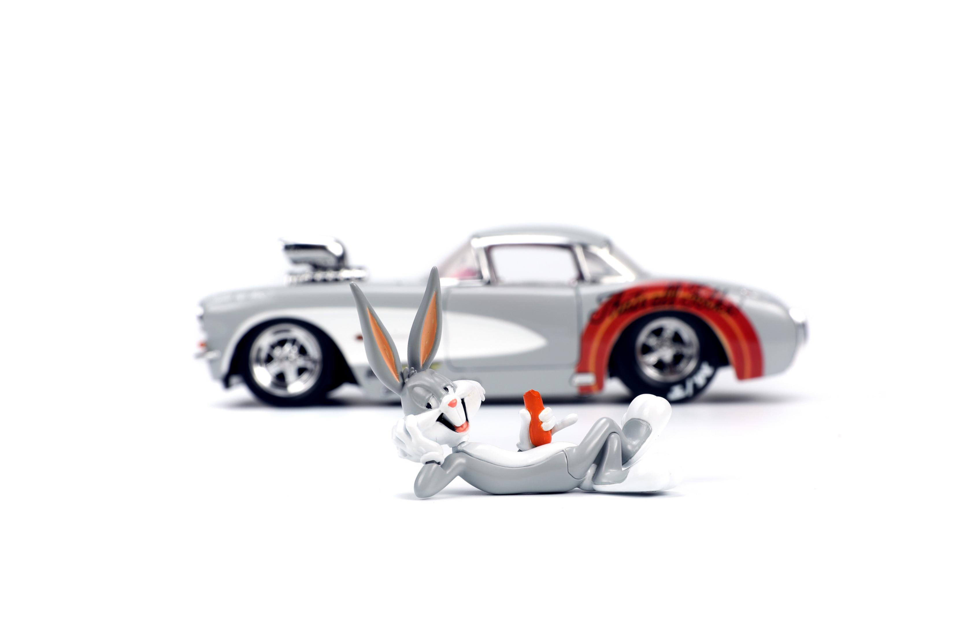 Bugs Bunny Figur, die sich in der Nähe eines Spielzeugautos zurücklehnt. Weißer Hintergrund.
