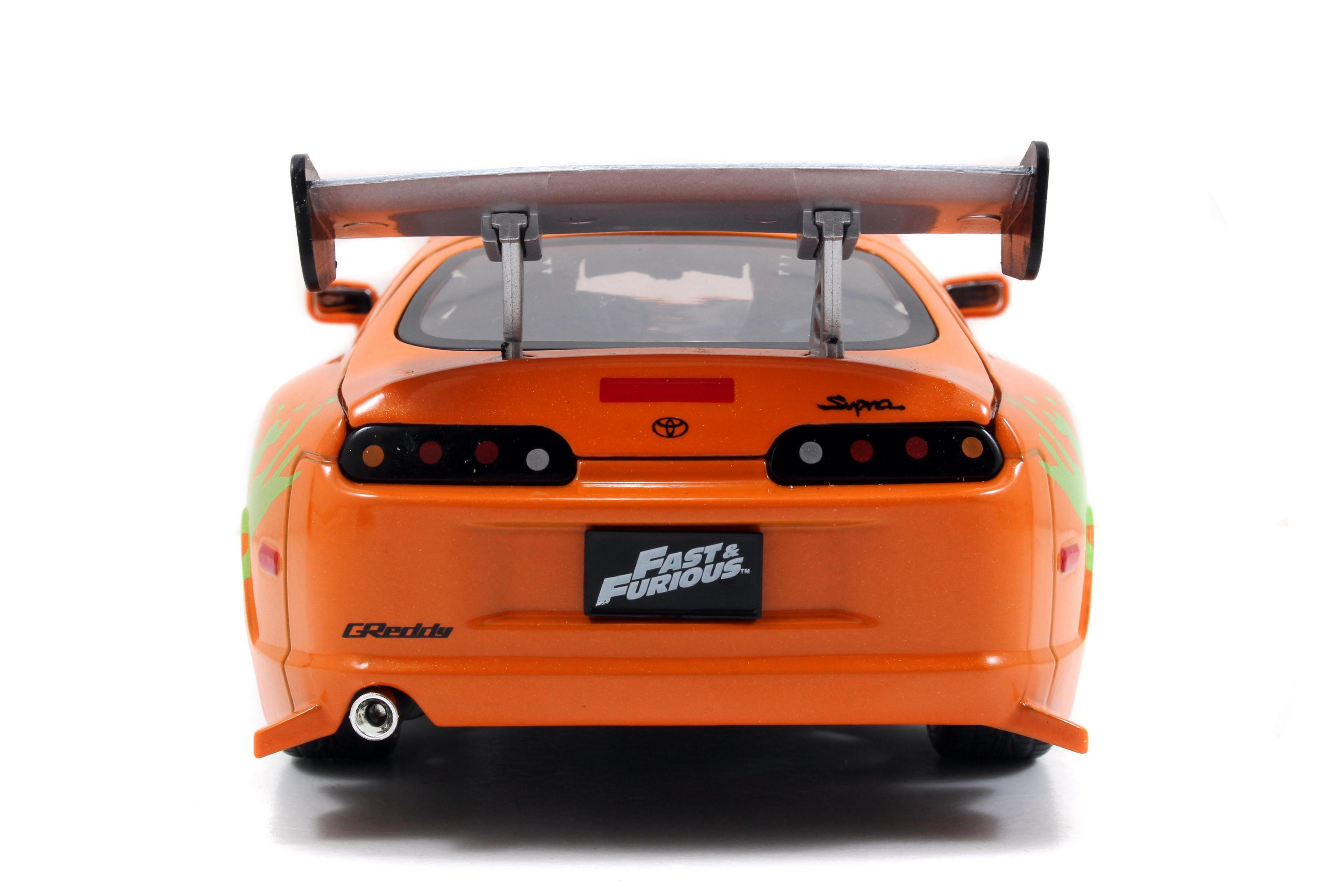 Rückansicht eines orangefarbenen Toyota Supra Spielzeugautos mit großem Spoiler und dem Fast & Furious Logo.
