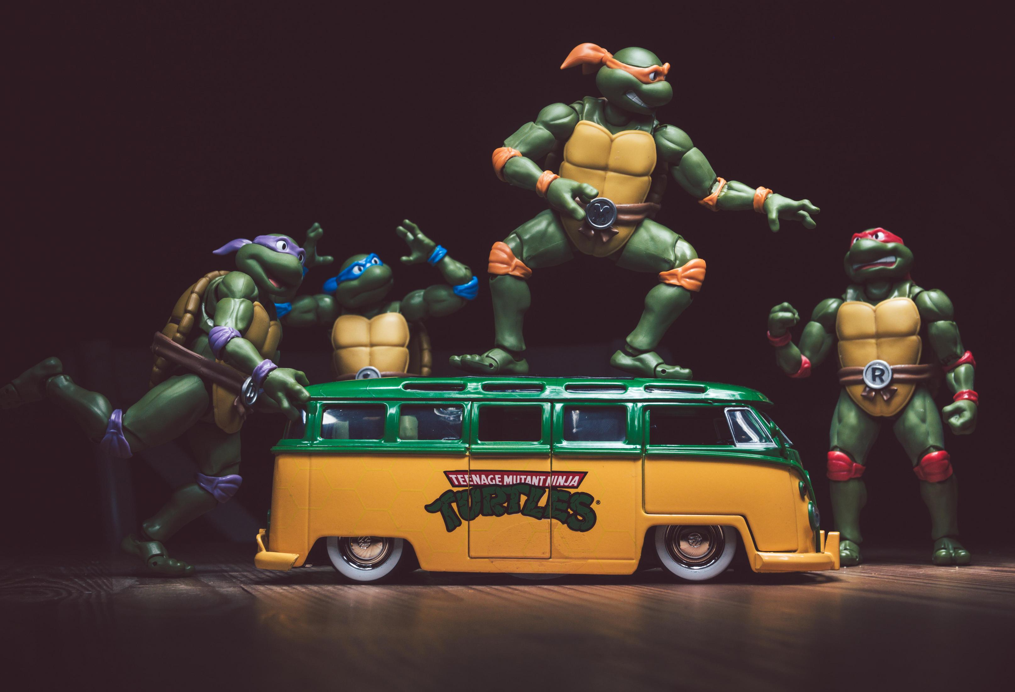 Teenage Mutant Ninja Turtles Figuren auf einem gelben Van. Dunkler Hintergrund.