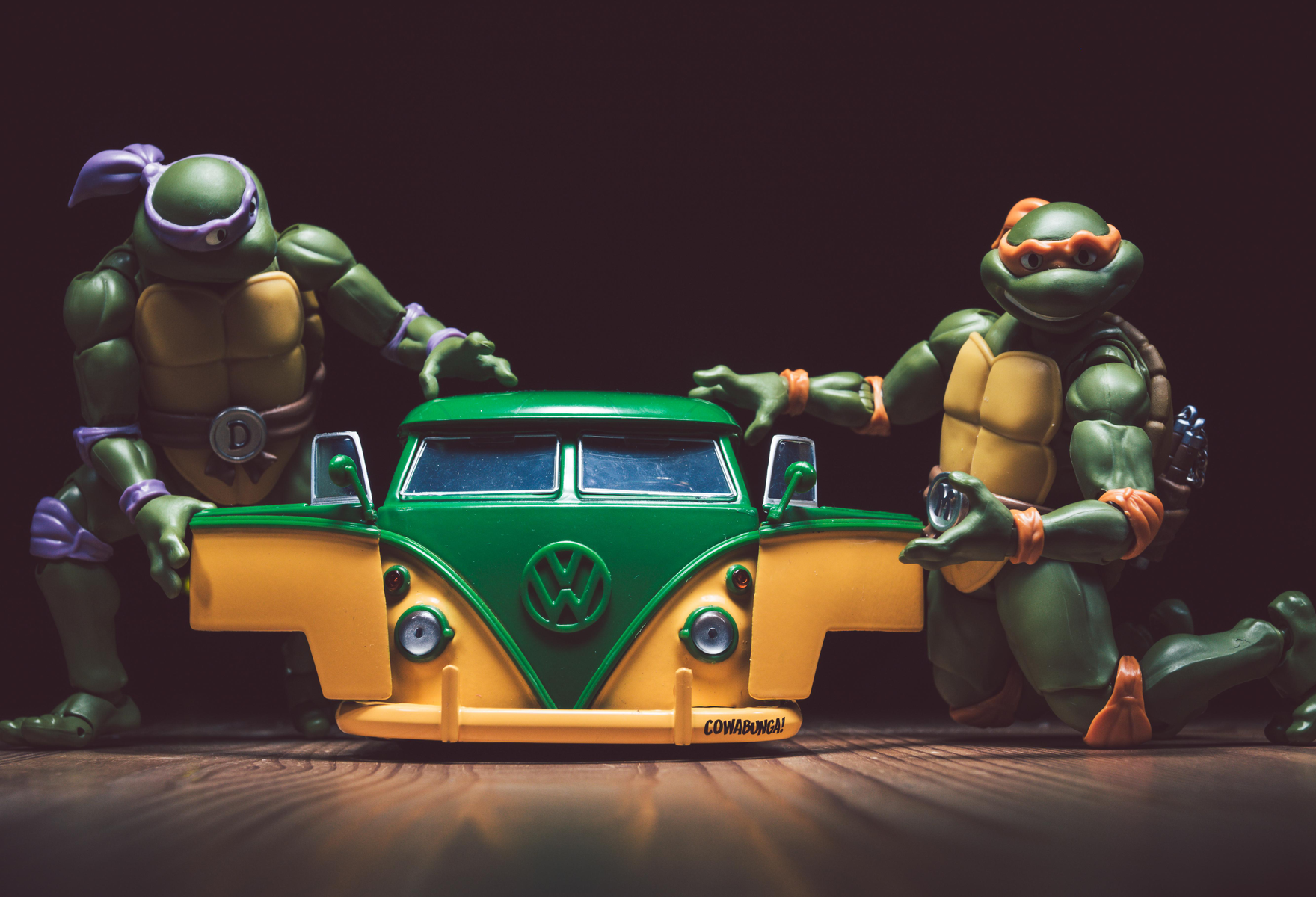 Teenage Mutant Ninja Turtles-Spielzeugfiguren neben einem grünen und gelben VW-Bus-Spielzeug.