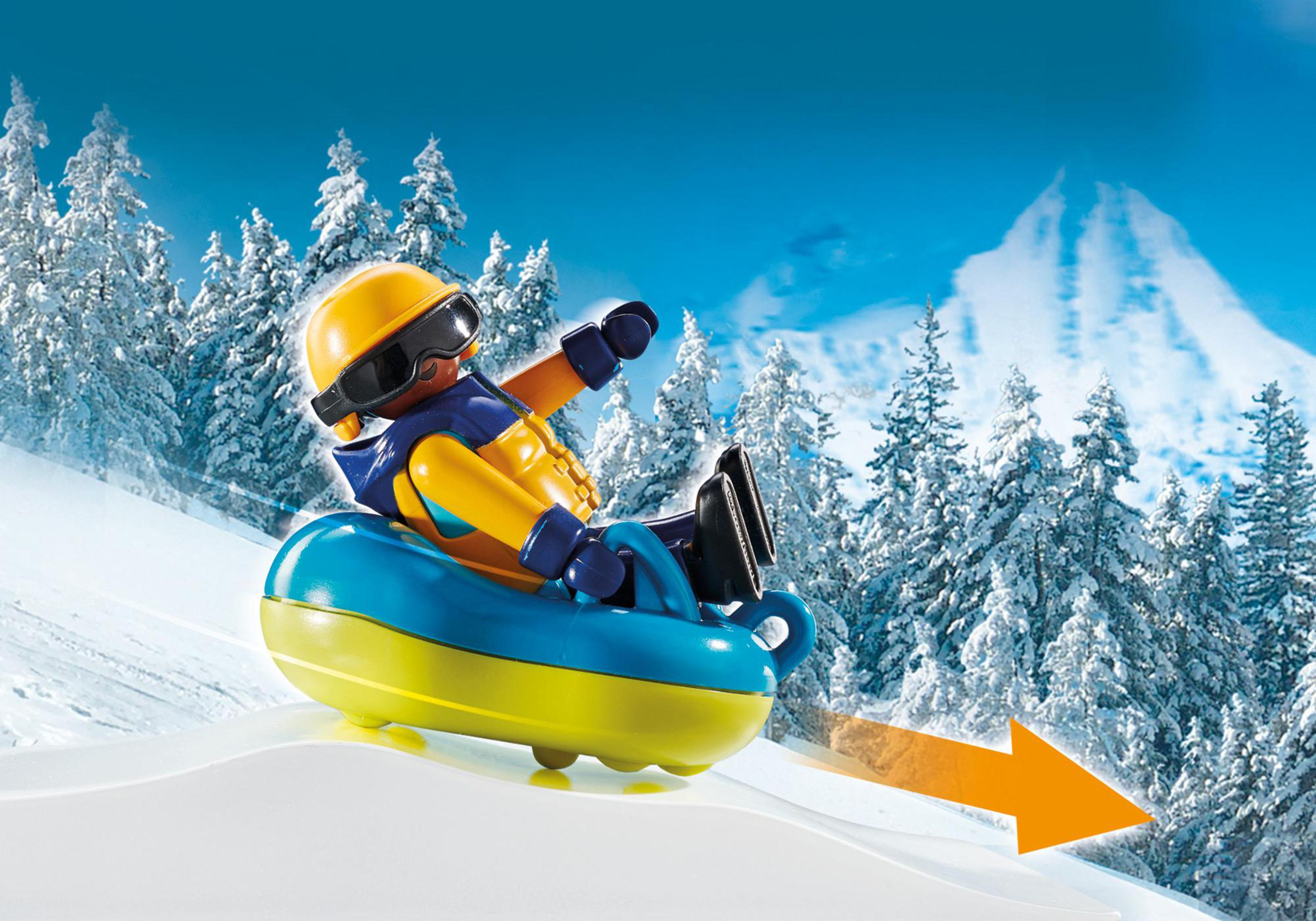 Personaggio Playmobil che fa slittino su una collina innevata. Montagne innevate sullo sfondo.