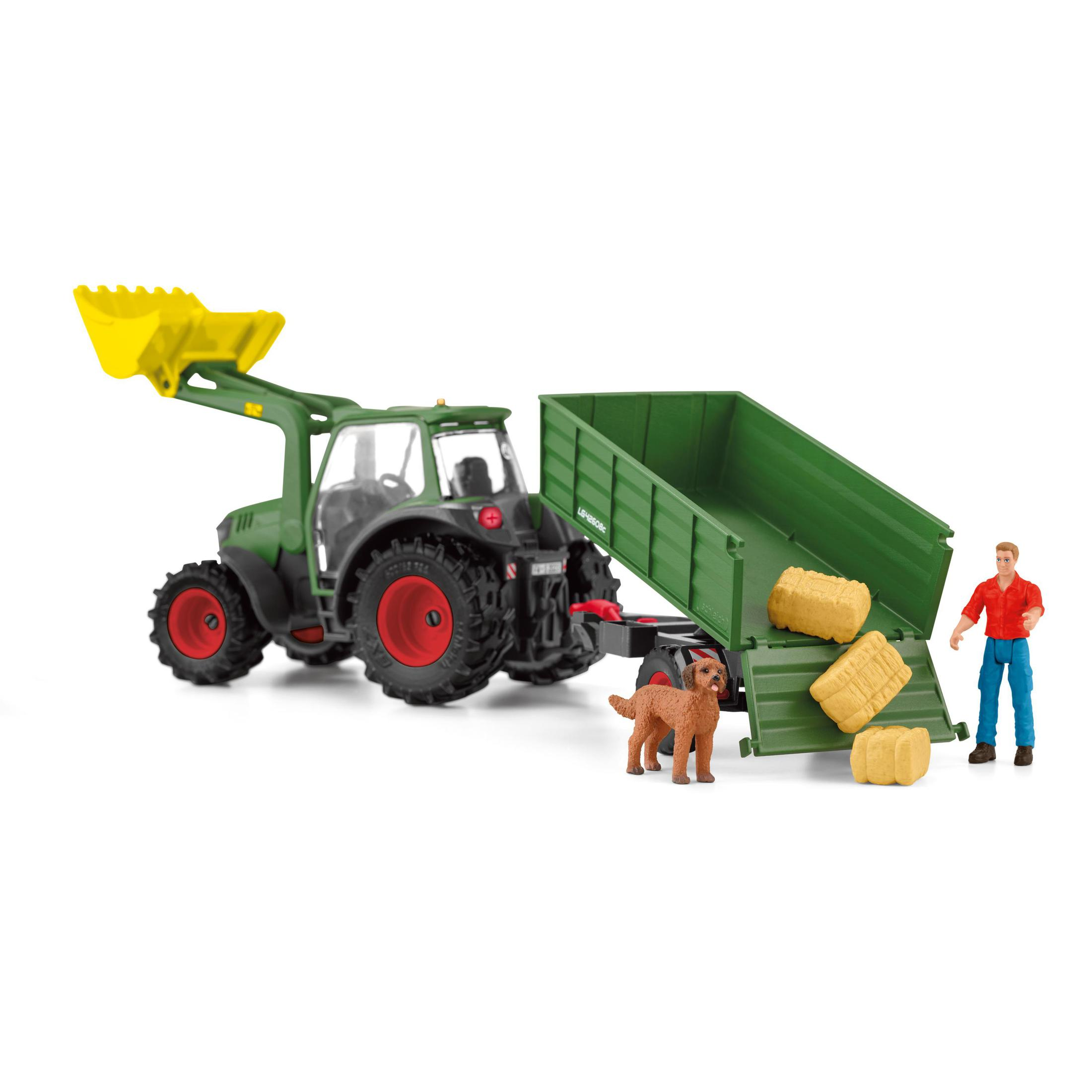 Grüner Traktor mit gelbem Lader, Anhänger, Heuballen, Hund und Person.