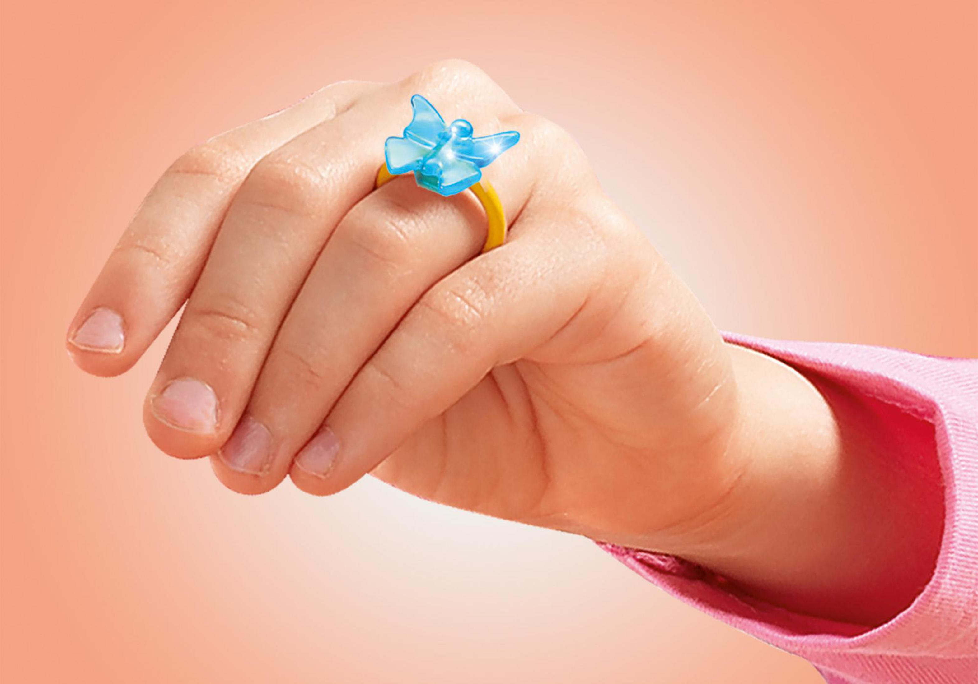 Una mano con un anello a farfalla giallo e blu su uno sfondo arancione.