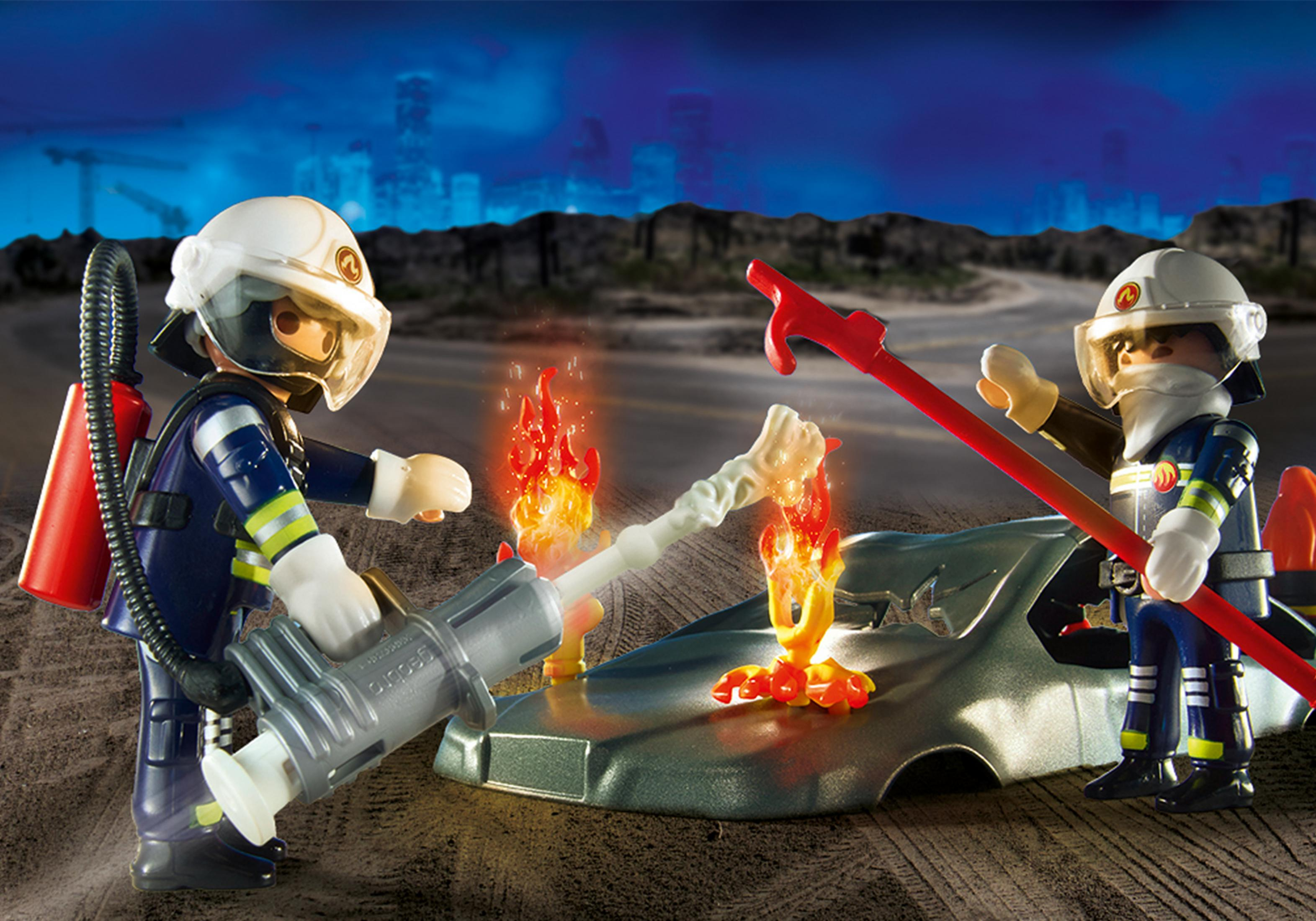 Bomberos Playmobil extinguiendo un incendio de coche con agua y herramientas.