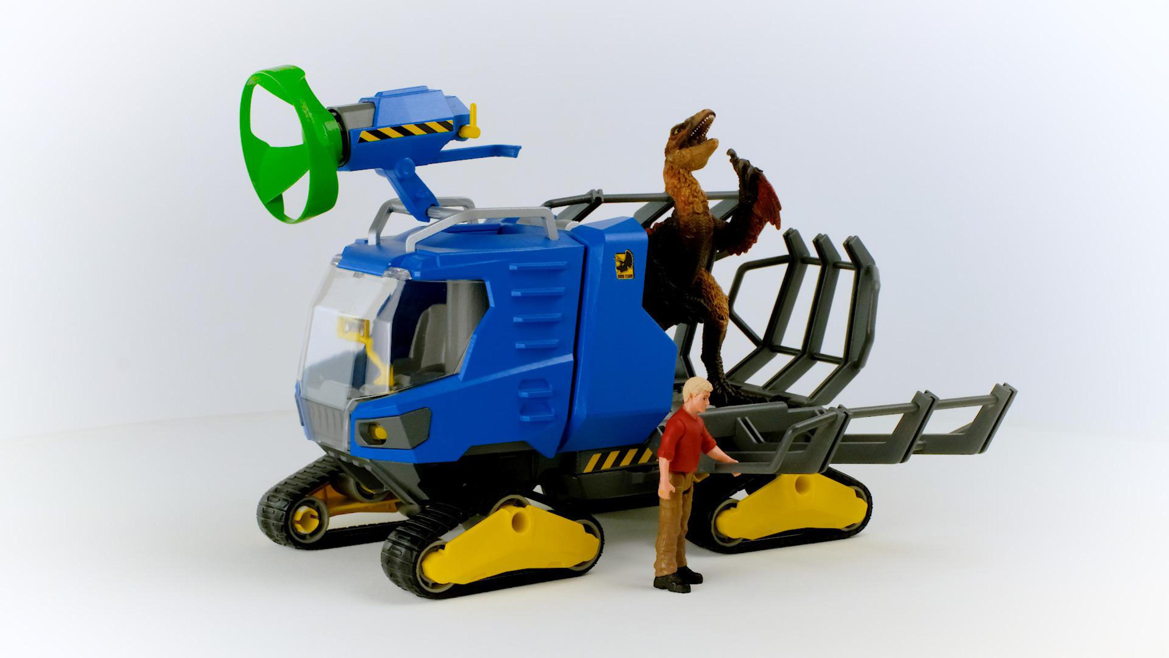 Toy dinosaur transport. A blue vehicle carries a dinosaur, a man stands beside it. The background is white.