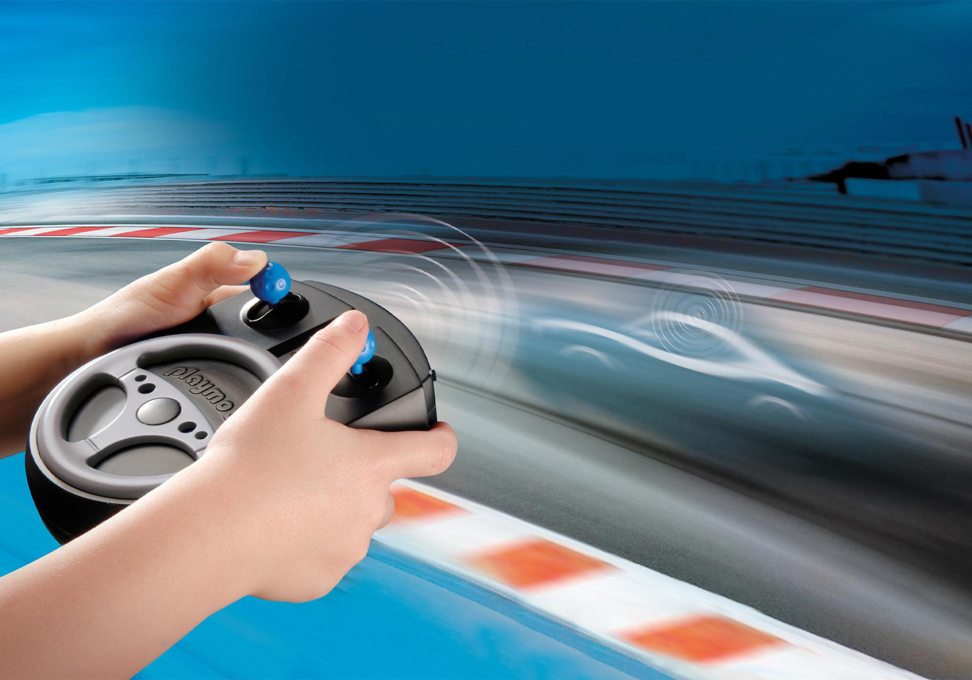 Hände halten einen Playmobil-Lenkrad-Controller mit verschwommenem Rennstreckenhintergrund.