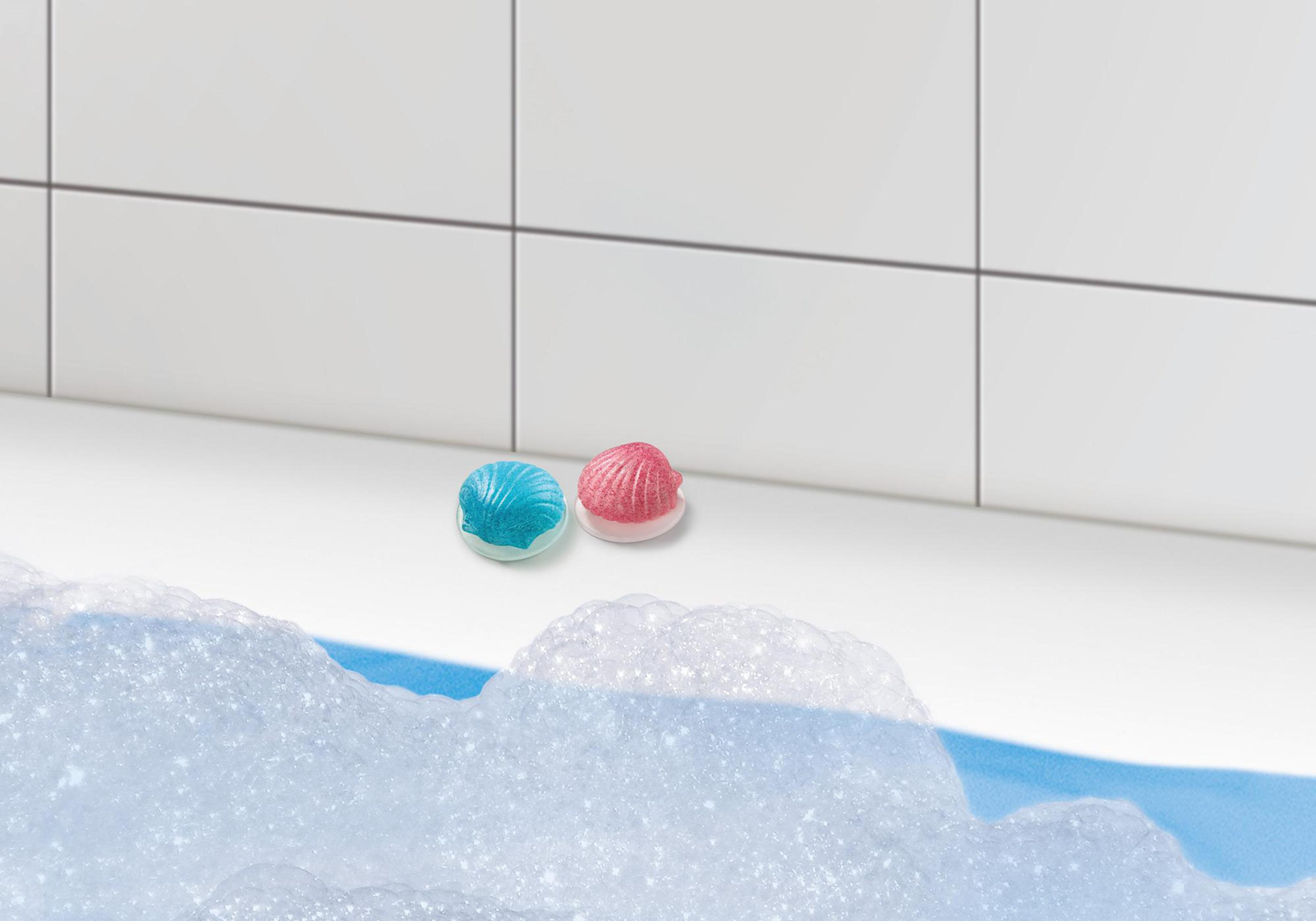 Due bombe da bagno, una blu e una rosa, su superficie bianca, con bolle.