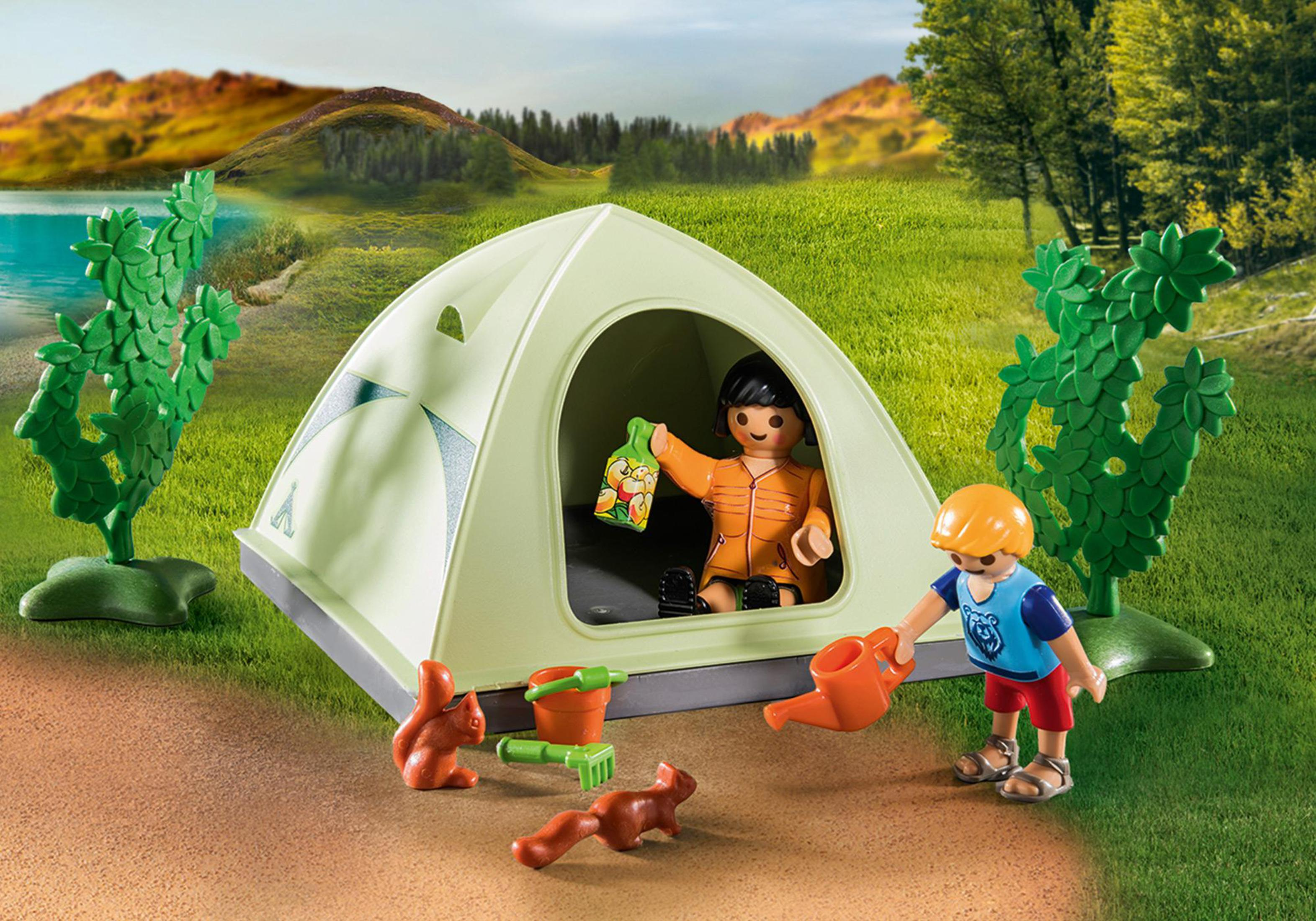 Una scena Playmobil con due bambini che campeggiano fuori da una tenda. Ci sono alberi e un lago.