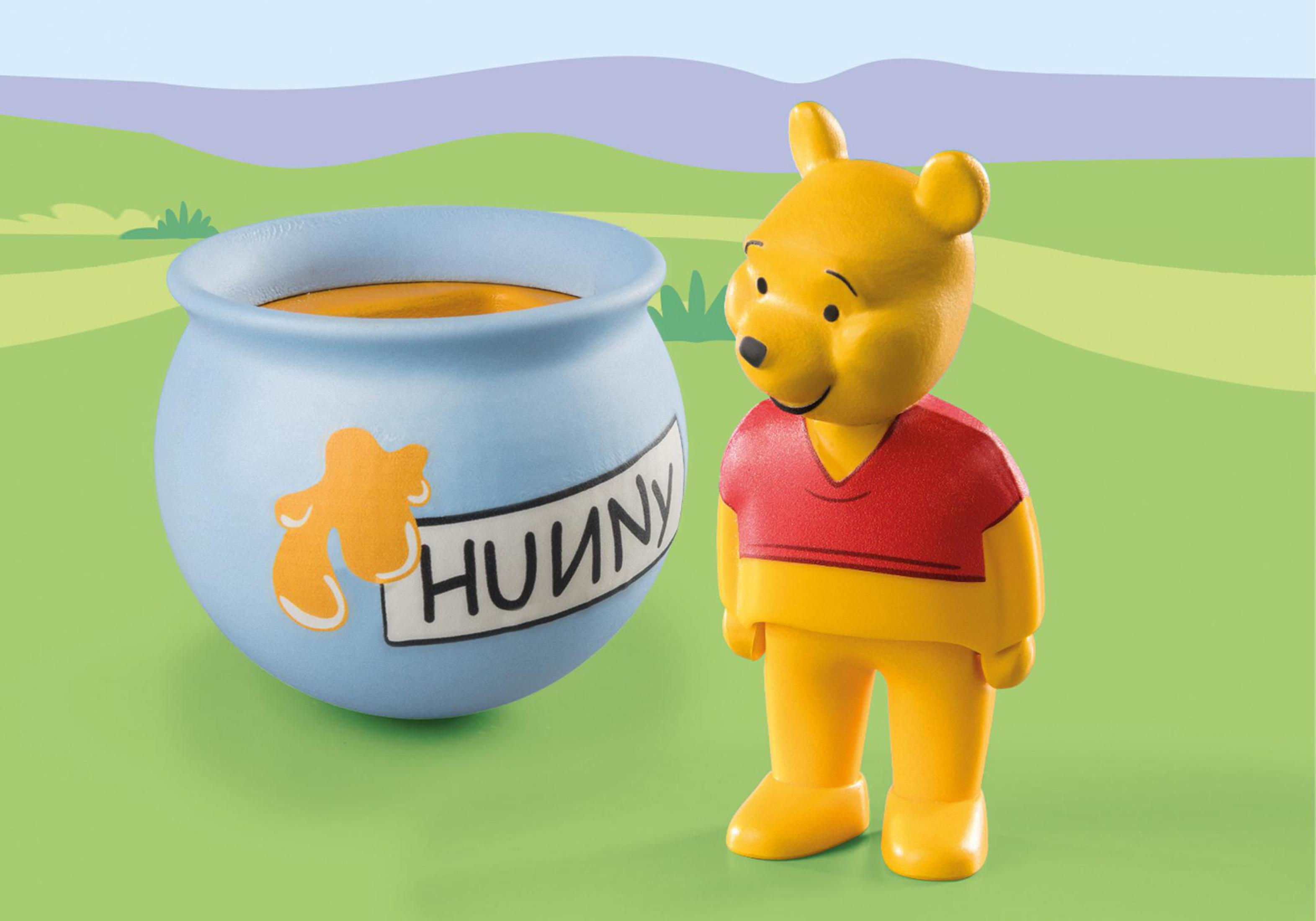 Winnie Puuh-Figur neben einem blauen Honigtopf mit "HUNNY". Grüner Gras-Hintergrund.