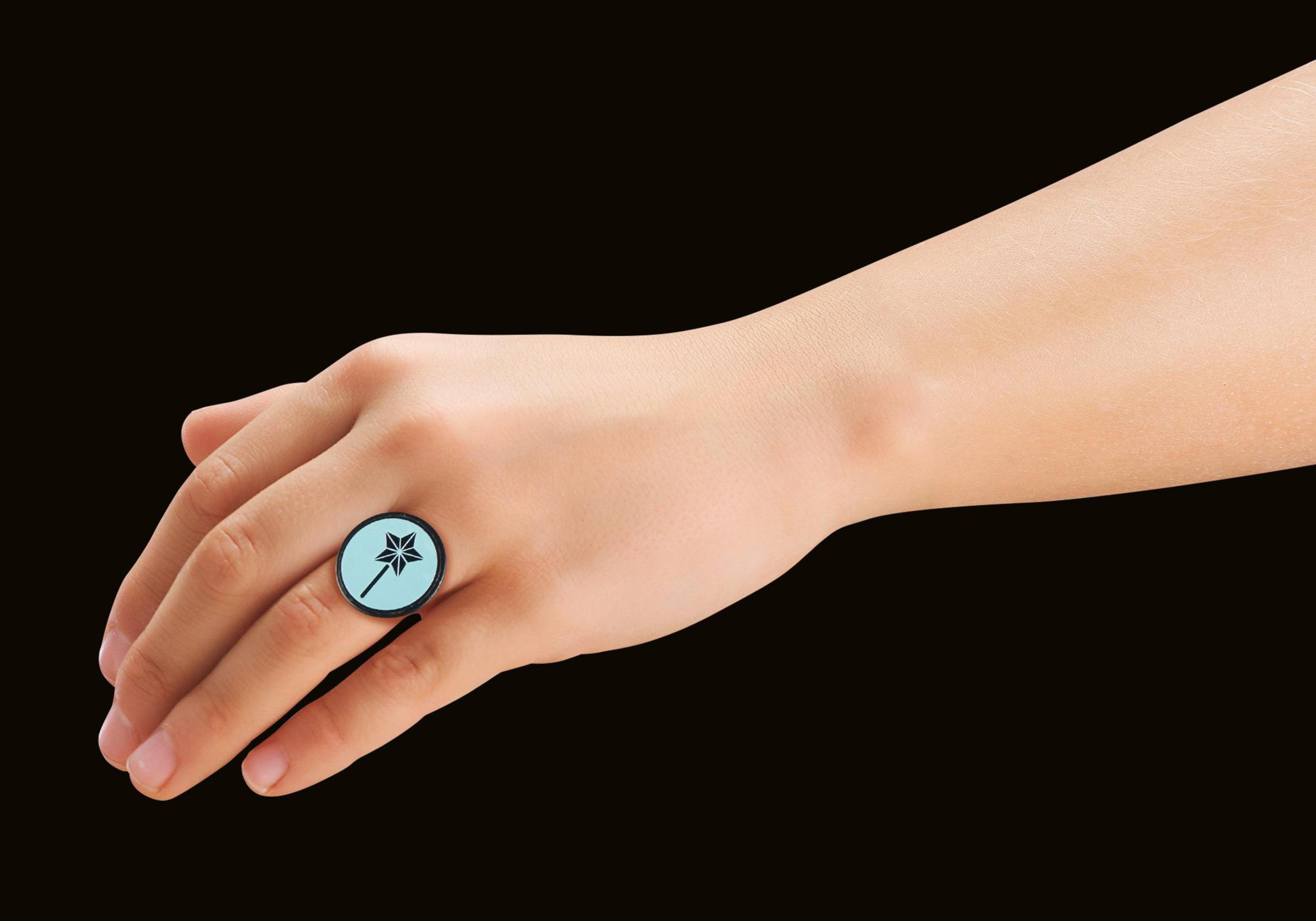 Hand, die einen blauen Ring mit Sterndesign hält, schwarzer Hintergrund.