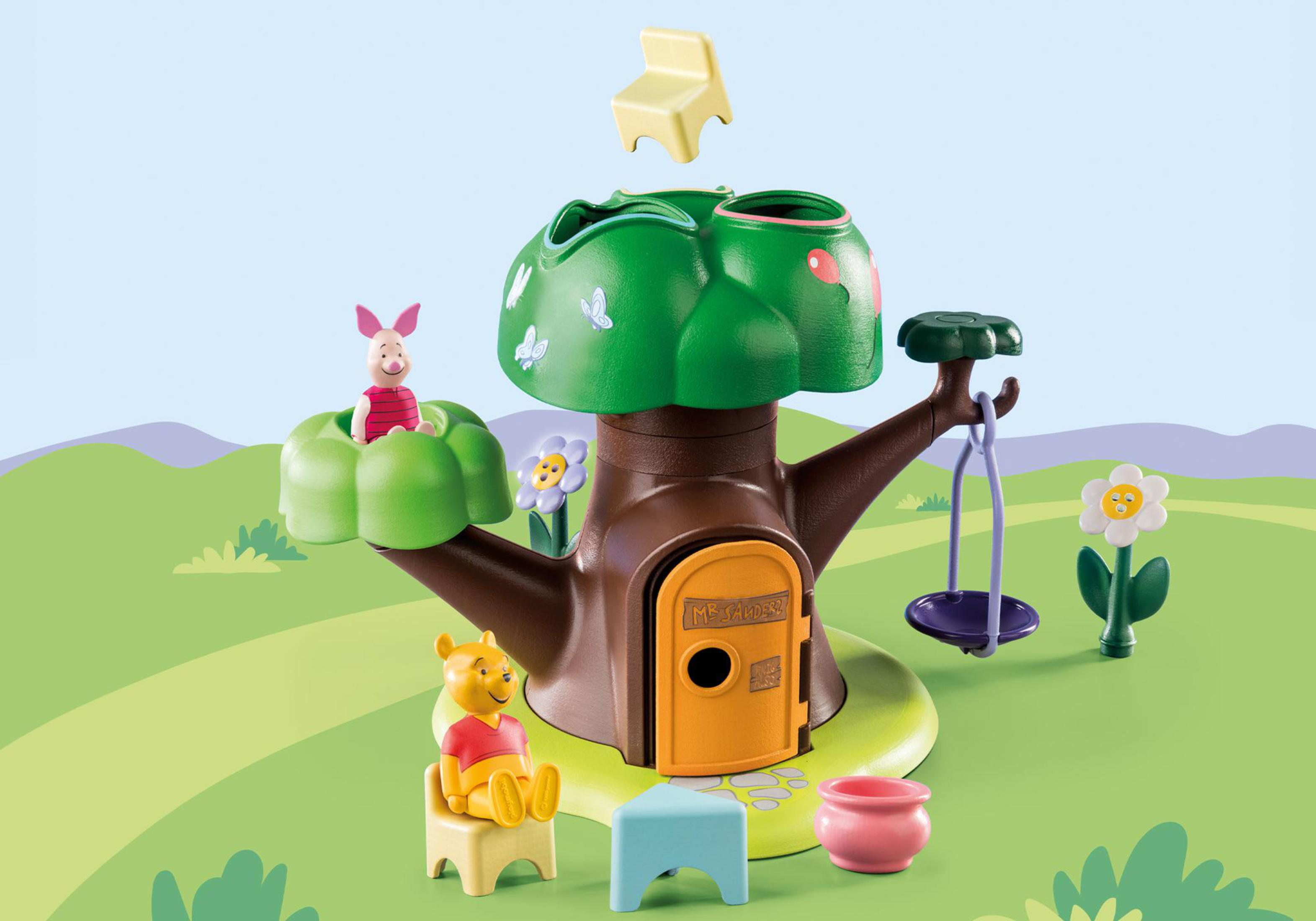 Ein Winnie-the-Pooh-Baumhaus-Spielset mit Ferkel, Winnie Puuh, Blumen und einer Schaukel auf einer grünen Wiese.