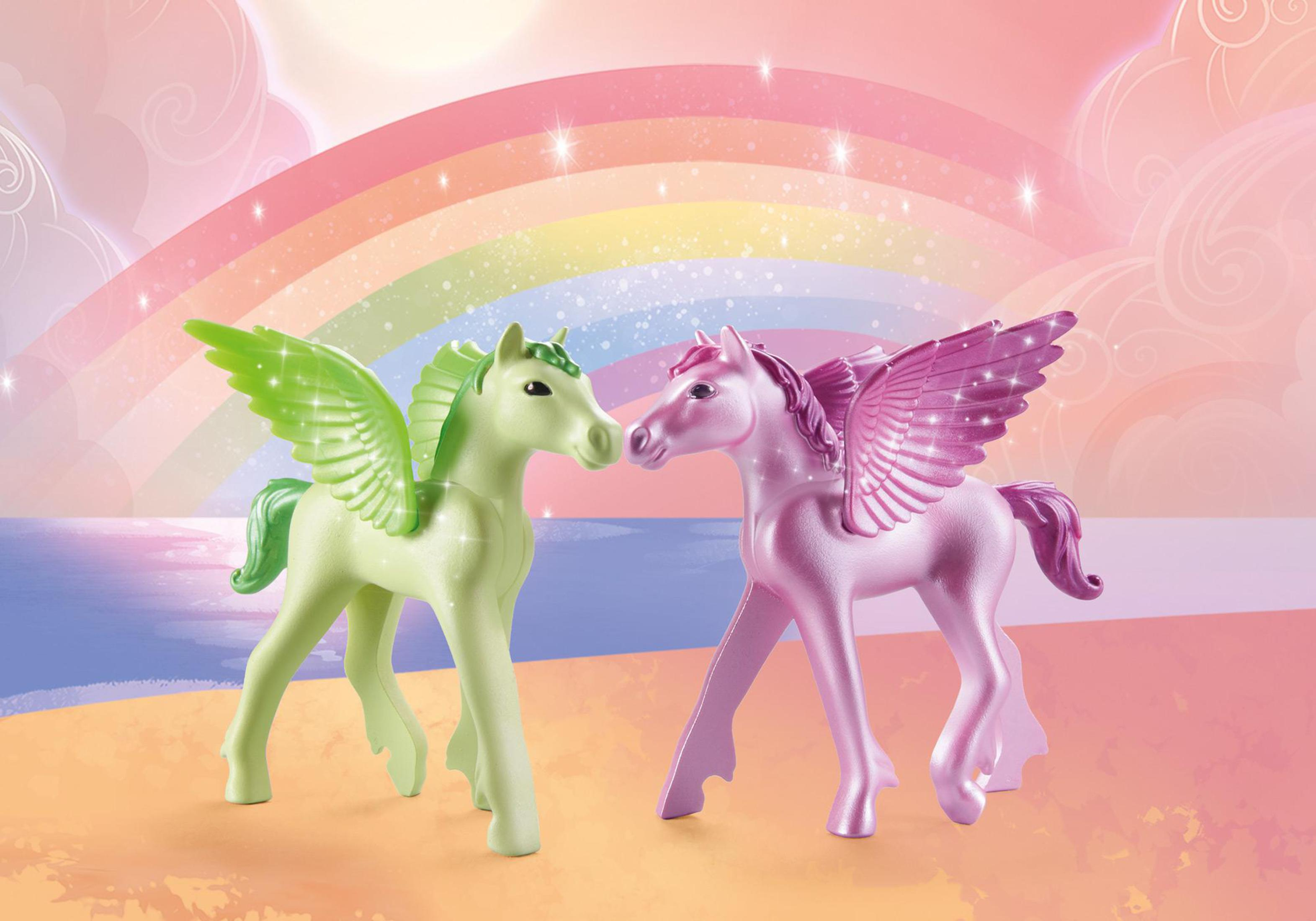 Zwei Spielzeug-Einhörner, eines grün mit grünen Flügeln und eines rosa mit rosa Flügeln, vor einem Regenbogen.
