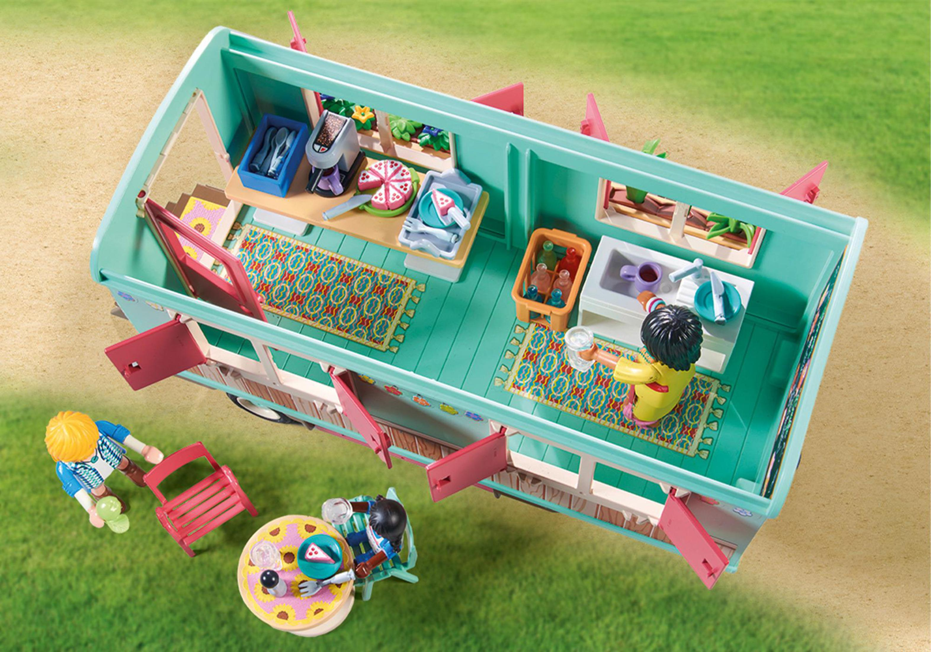 Interno del food truck Playmobil con personaggi, cibo e sedute su sfondo verde.