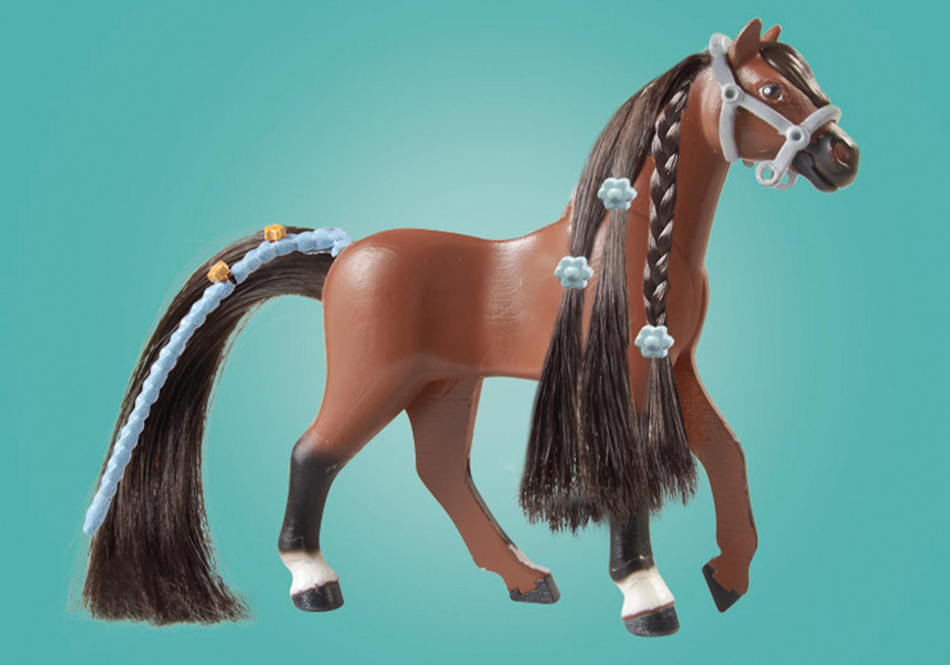 Cavallo giocattolo marrone con criniera e coda nera intrecciata. Decorazioni blu. Sfondo turchese. Brida bianca.