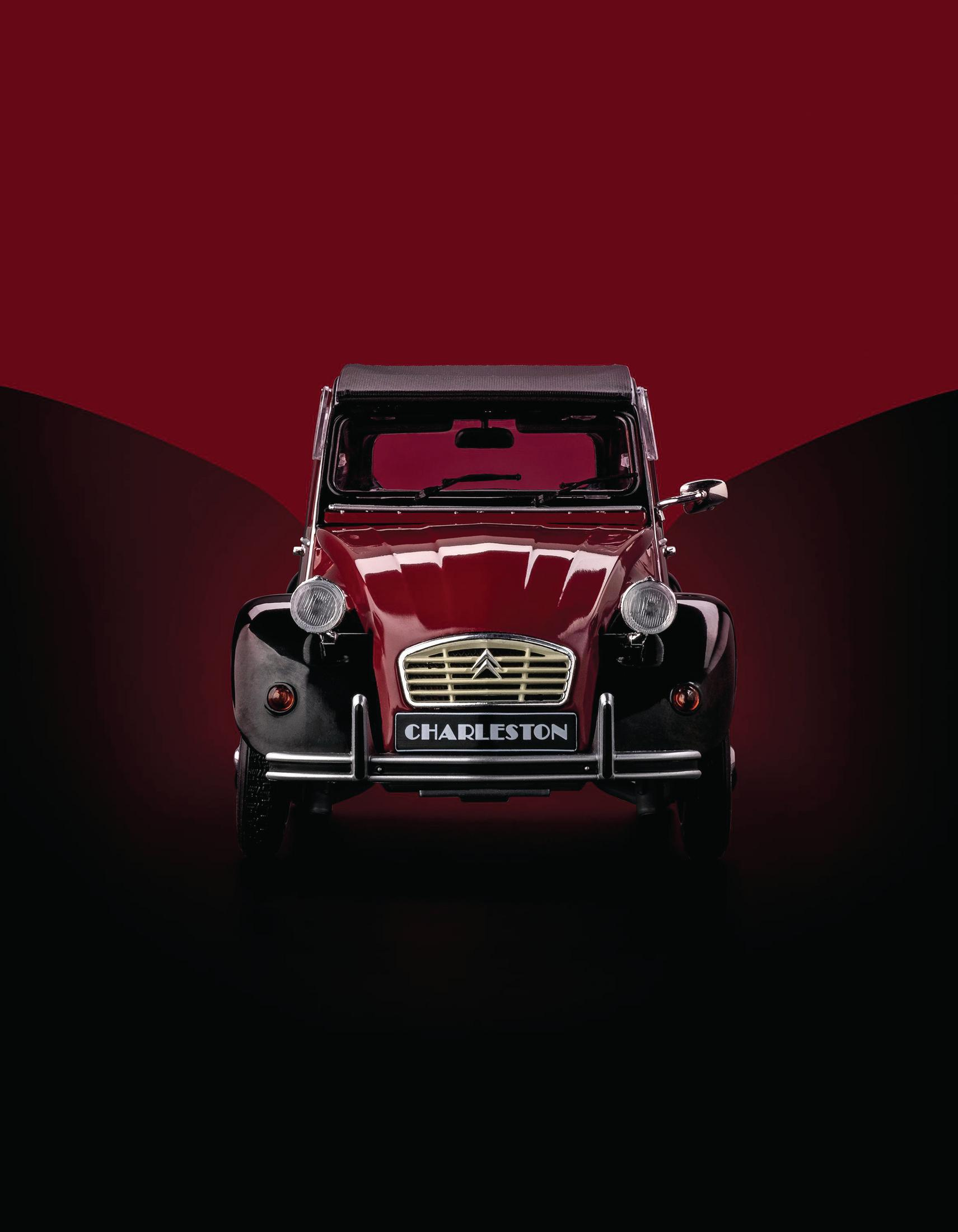 Ein rotes klassisches Auto, der Citroën 2CV, vor rotem und schwarzem Hintergrund.