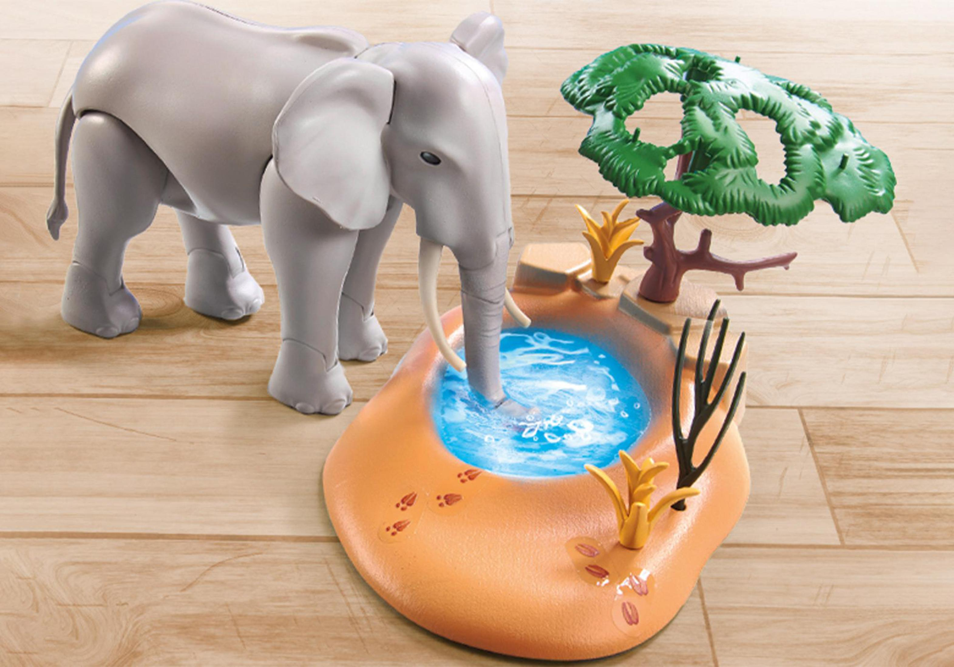 Playmobil Elefanten-Spielzeug in der Nähe eines Wasserlochs. Der Elefant trinkt Wasser.