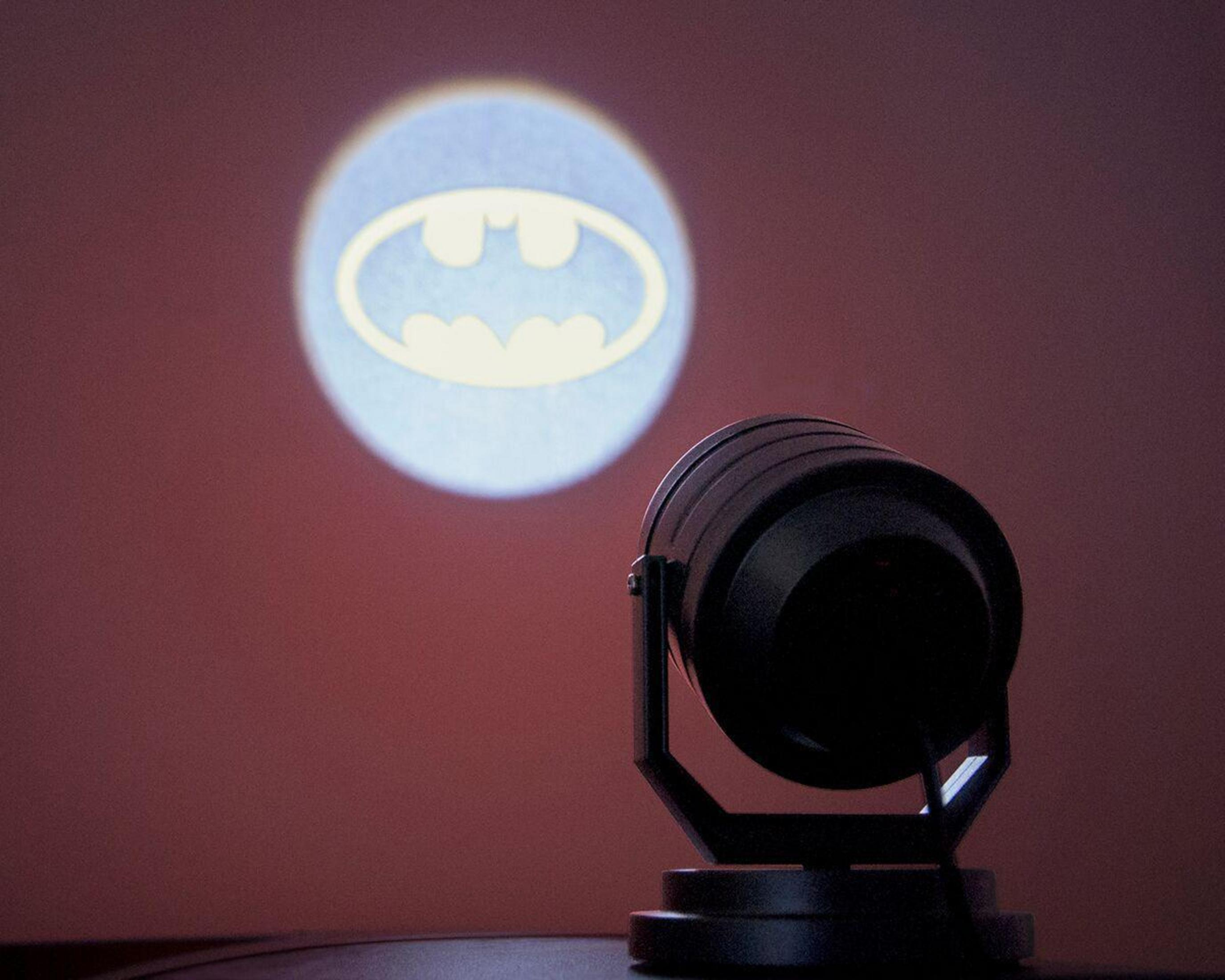 Ein Batman-Logo, das auf eine Wand projiziert wird. Ein Scheinwerfer scheint das Fledermaussymbol auf die Oberfläche.