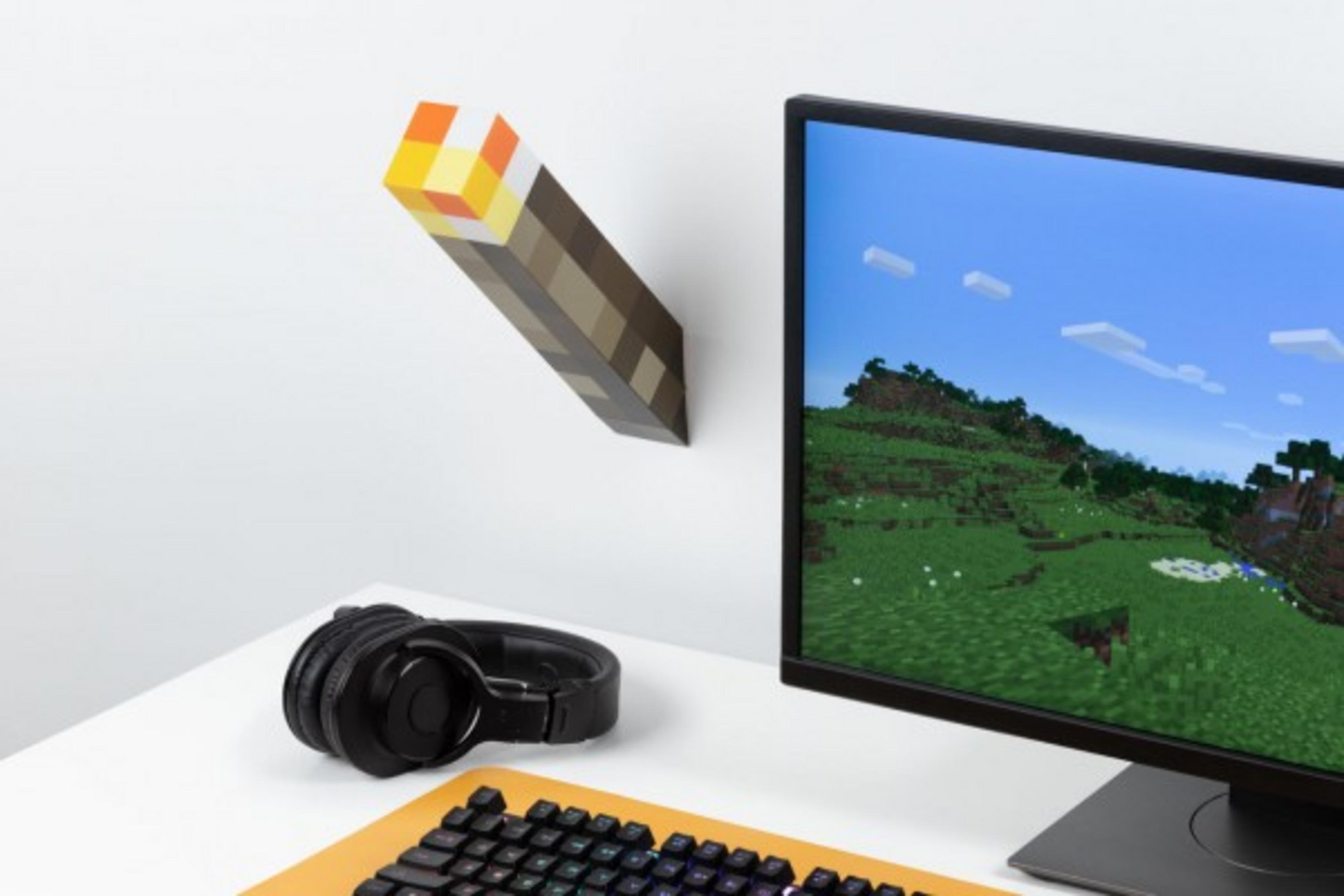Minecraft-Fackel an der Wand, Computermonitor zeigt Spielszene, schwarze Kopfhörer, Tastatur.