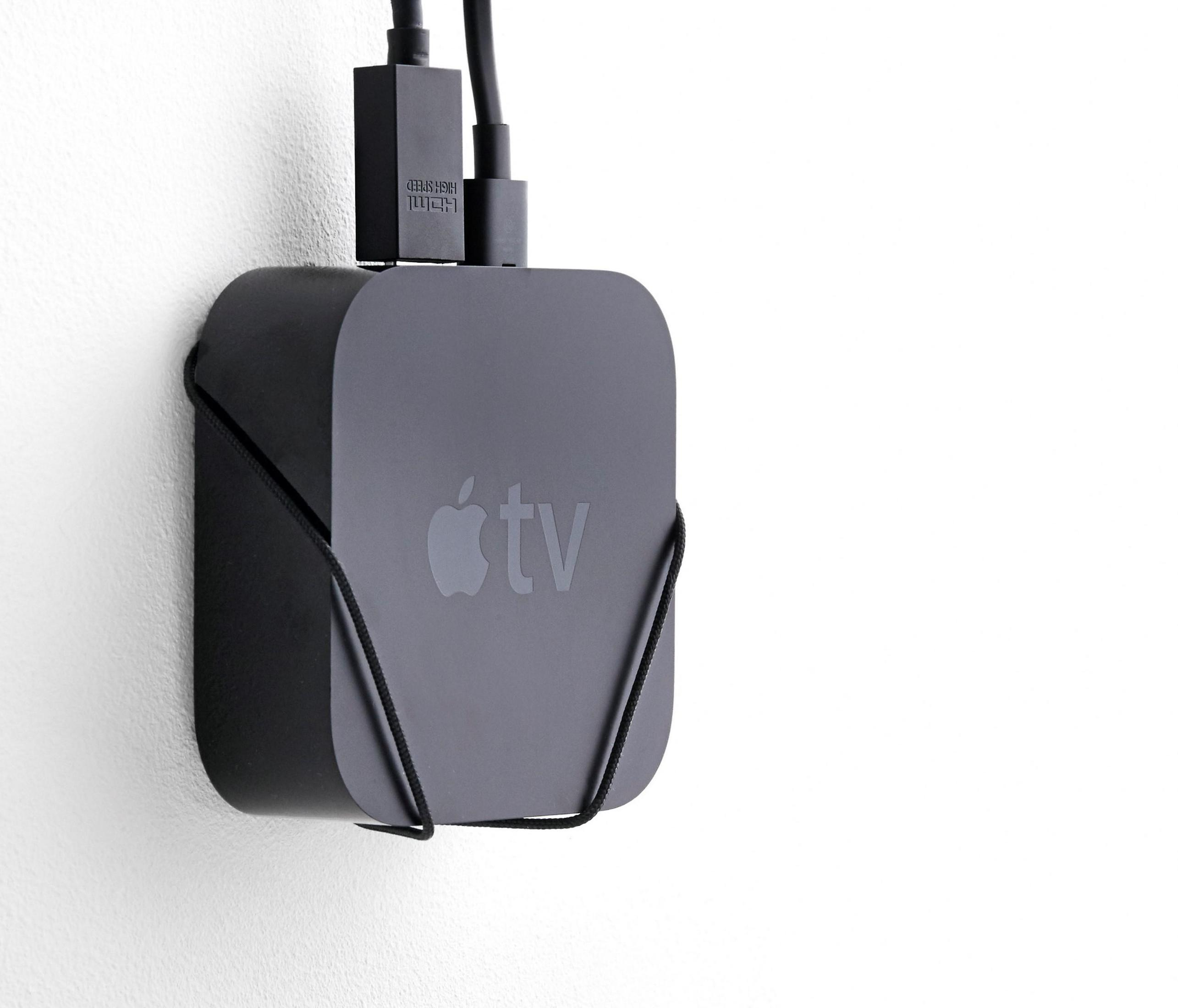 Apple TV-Gerät an einer weißen Wand montiert, mit angeschlossenen Kabeln.