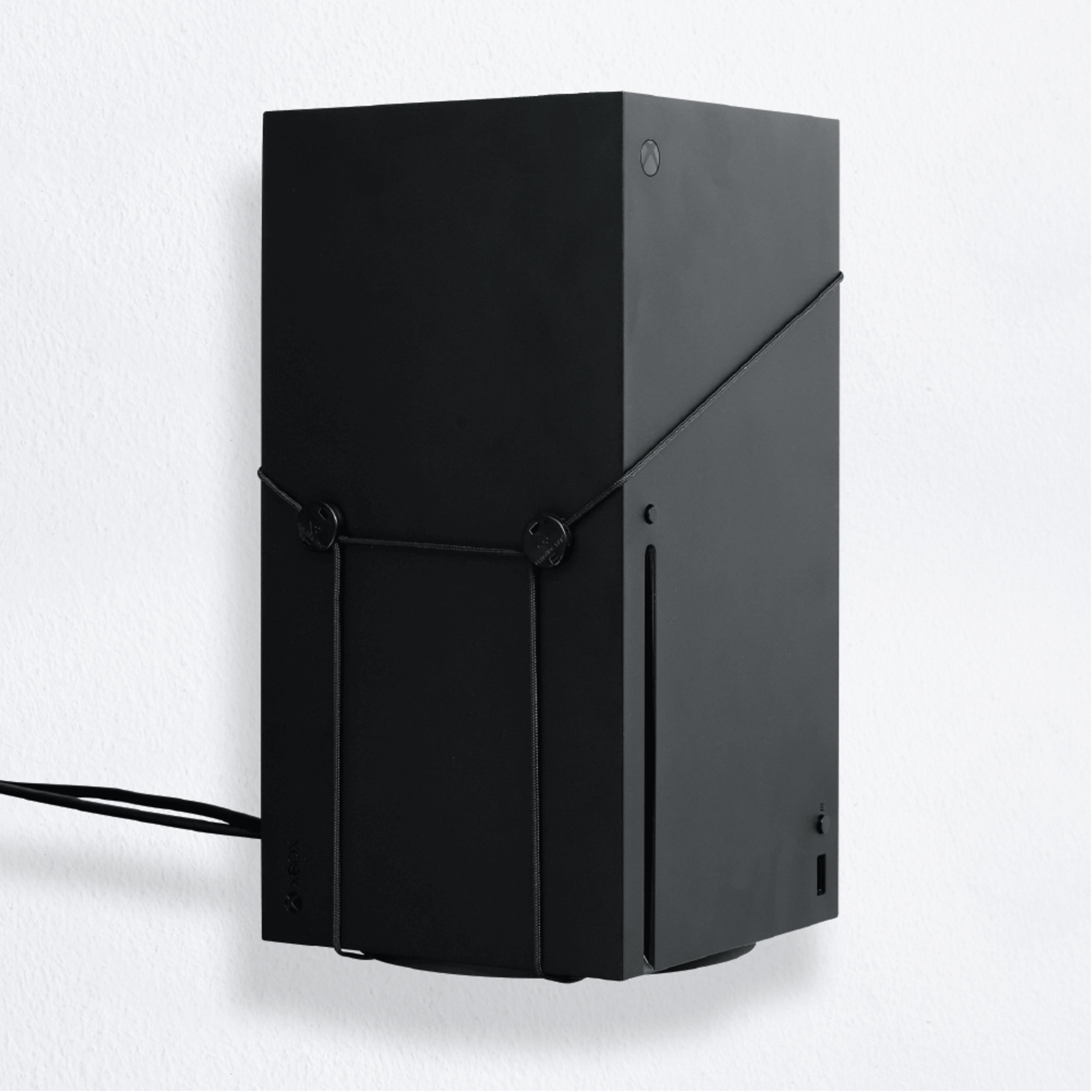 Czarna konsola do gier jest zamontowana na białej ścianie z czarnymi paskami.