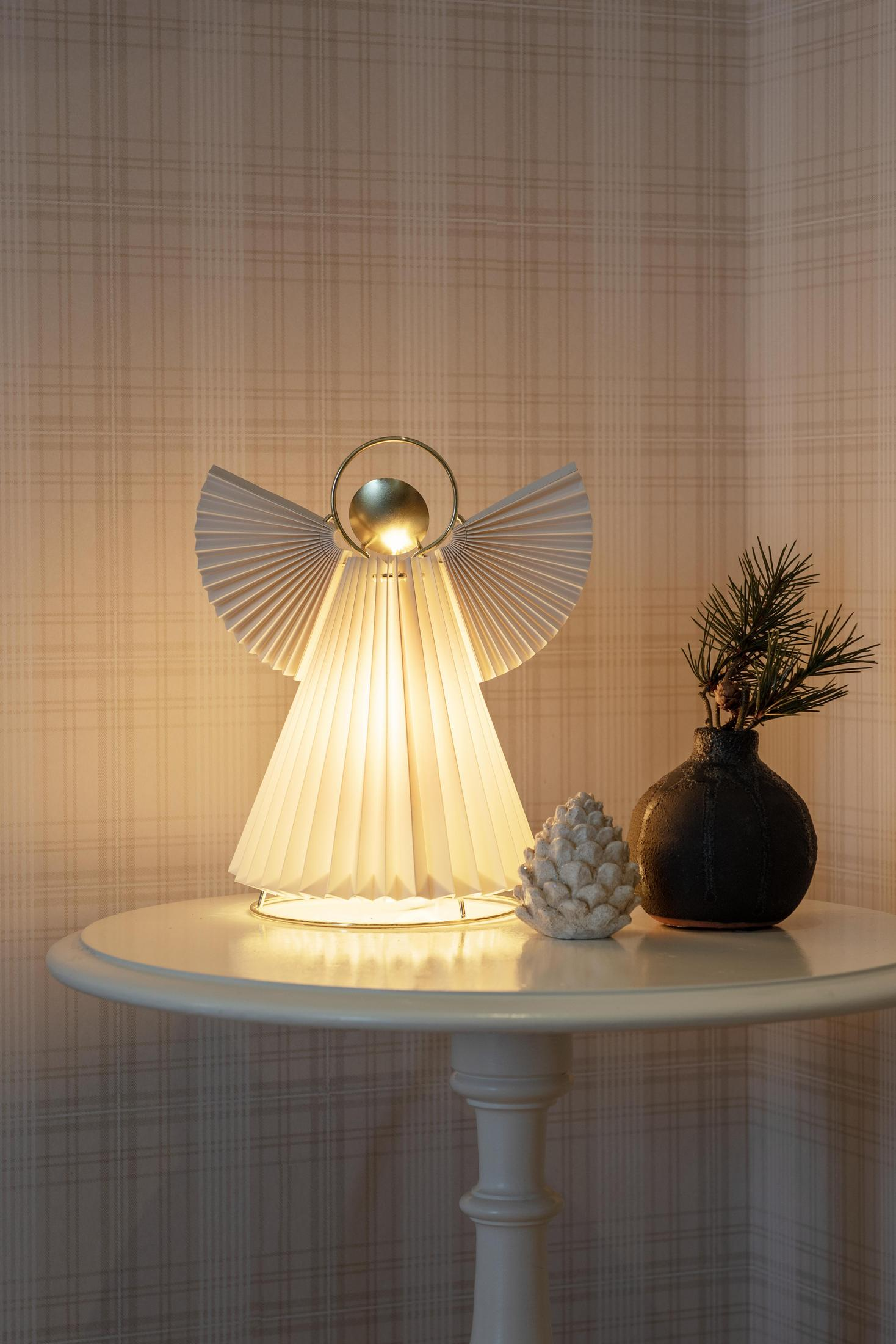 Engelförmige Lampe mit hellem Licht auf einem Tisch.