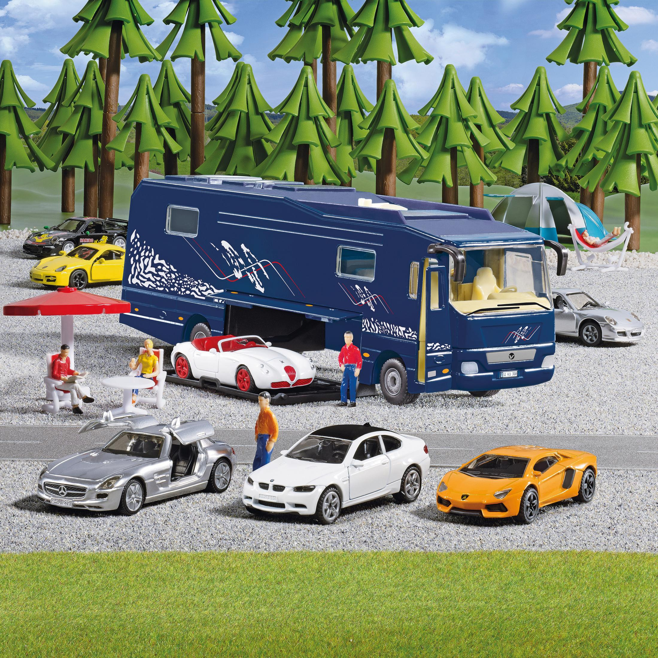 Niebieski autobus zabawkowy zaparkowany z innymi zabawkami, ludźmi i drzewami. Zielona trawa i błękitne niebo.