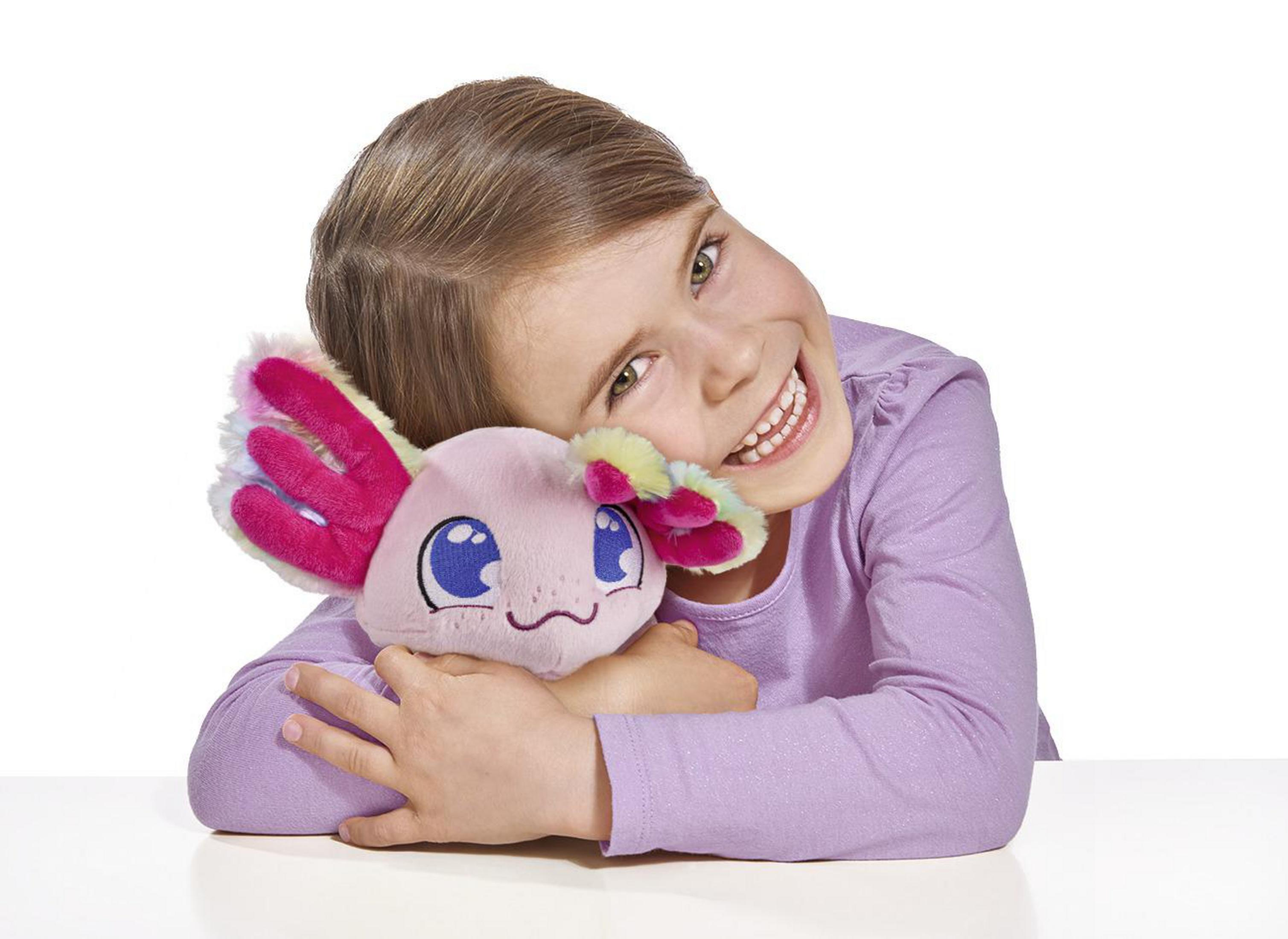 Ein junges Mädchen umarmt ein pinkfarbenes Axolotl-Plüschtier mit lächelndem Gesicht.
