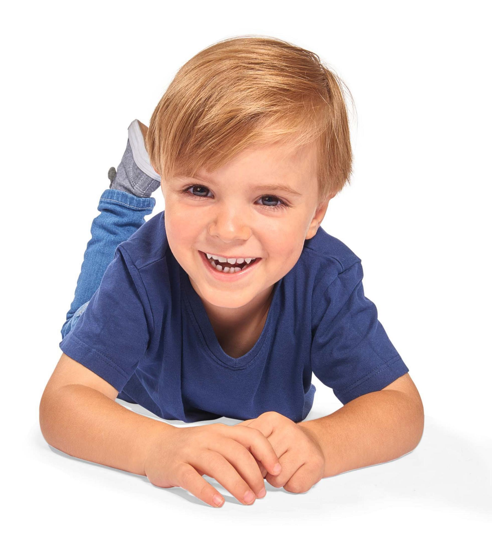 Uśmiechnięte małe dziecko leżące na podłodze, w niebieskiej koszuli i dżinsach.