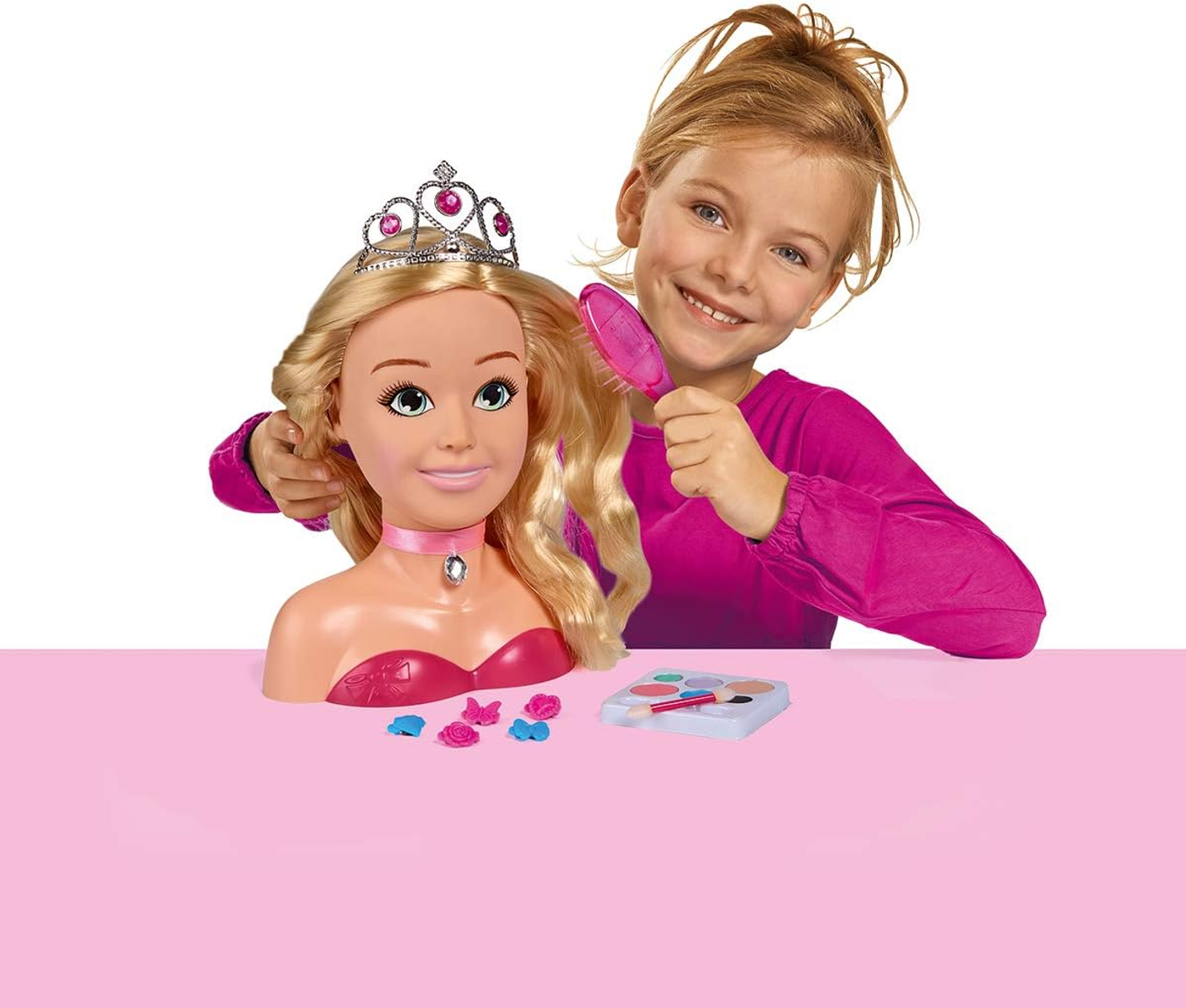 Ein Mädchen stylt Haare und Make-up einer Puppe auf rosa Hintergrund.