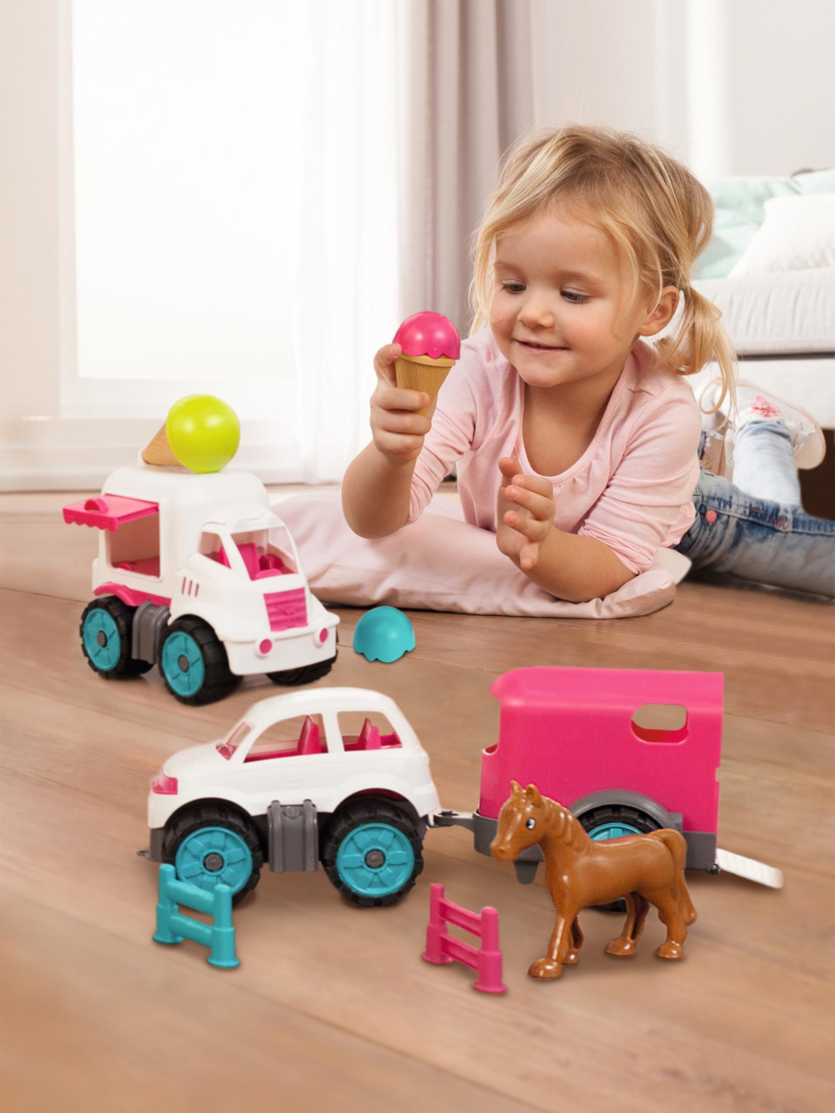 Dziecko bawi się zabawką, lodziarnią, samochodem i koniem z przyczepą. Drewniana podłoga.