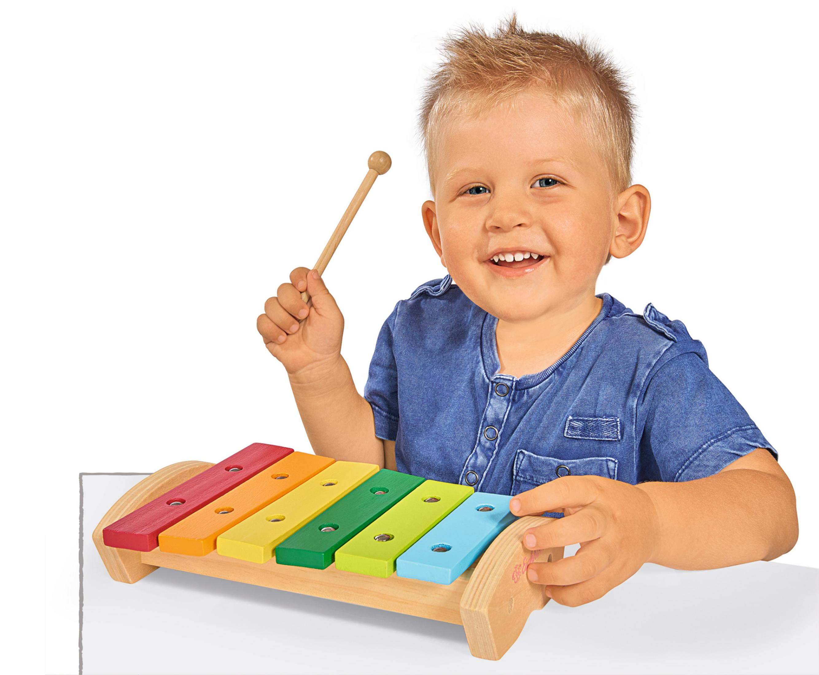 Blonder Junge lächelt, hält einen Schlägel über einem bunten Spielzeug-Xylophon.