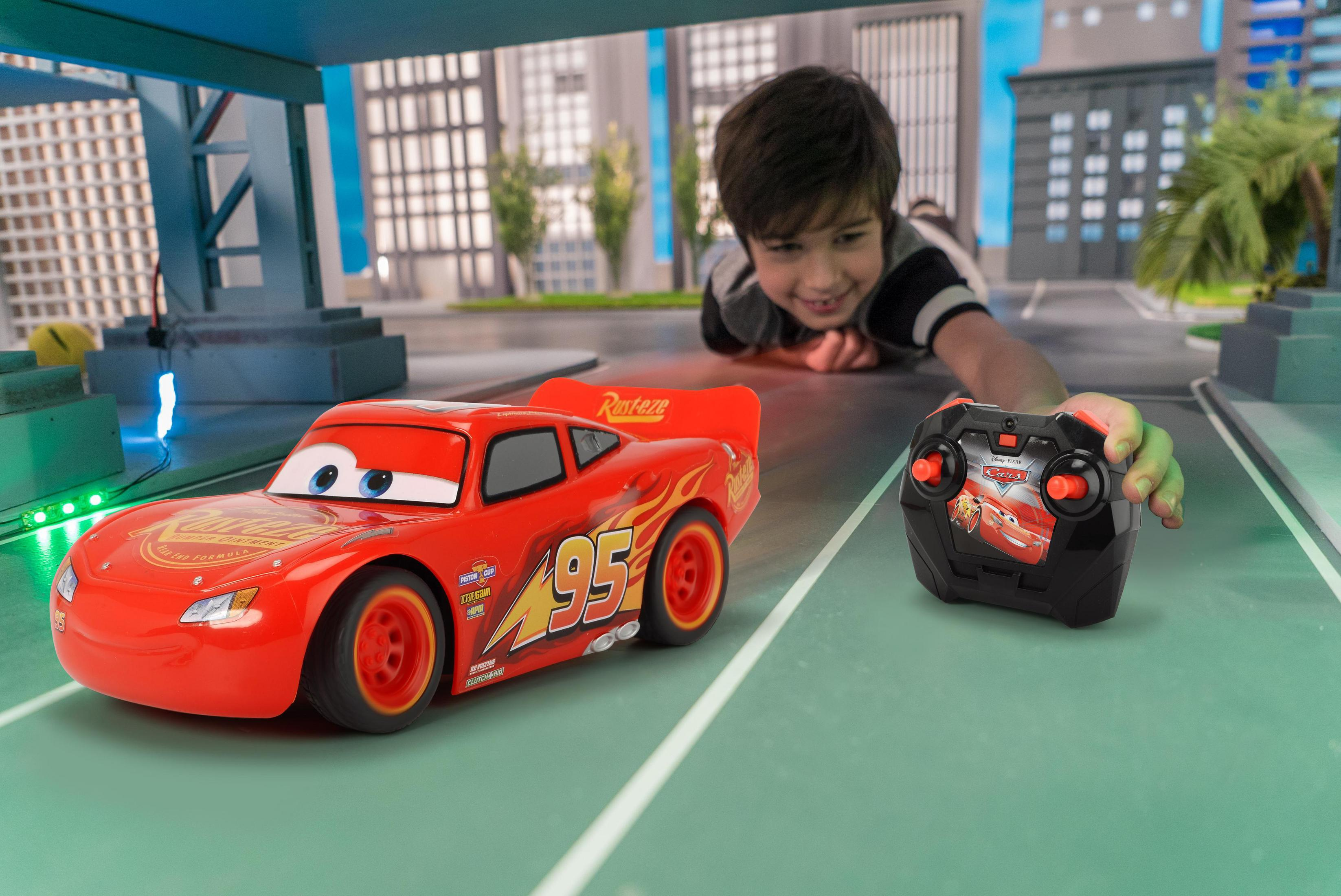 Un niño que alcanza un mando a distancia junto a un coche de juguete.
