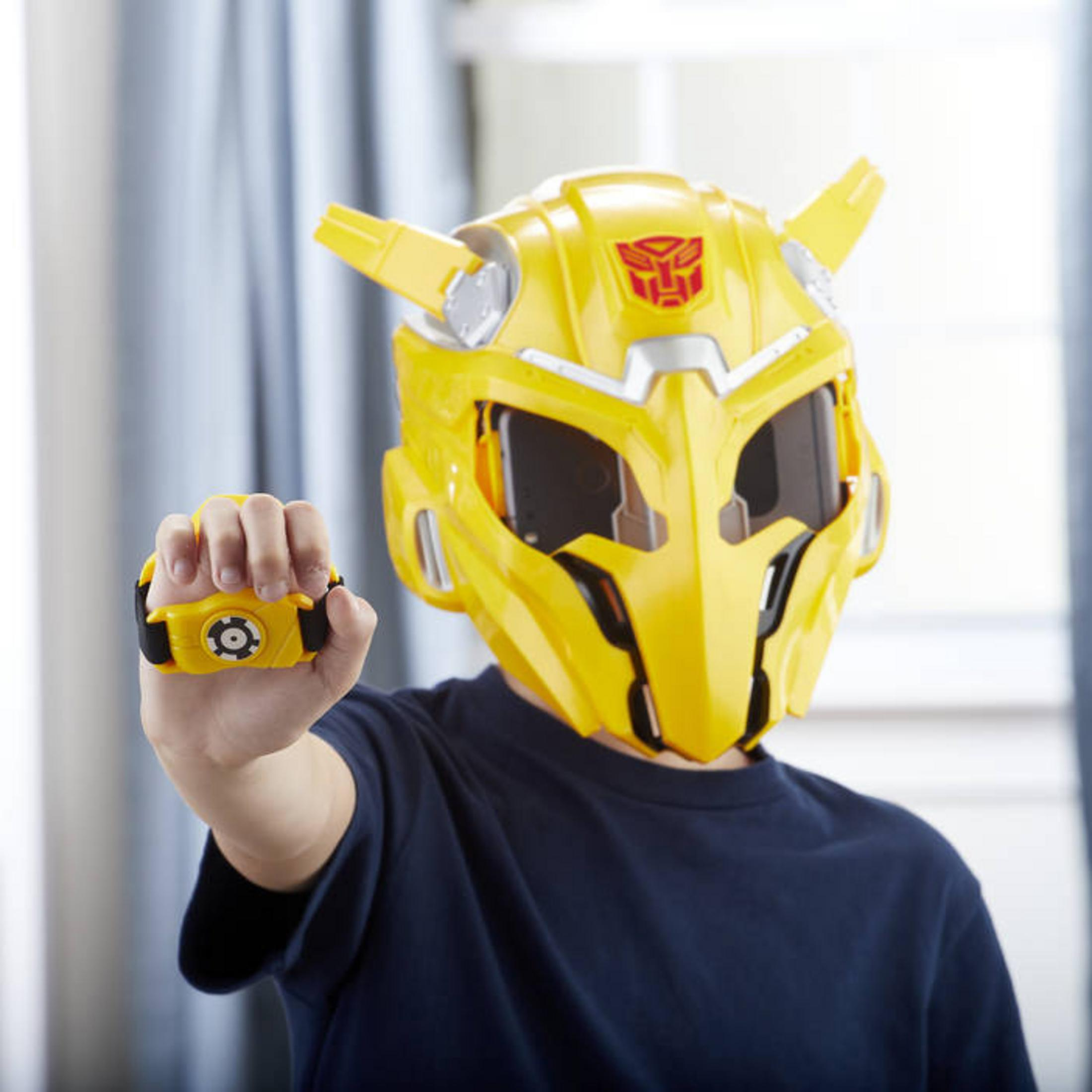 Ein Kind trägt eine gelbe Transformer-Maske mit einem gelben Gerät in der Hand.