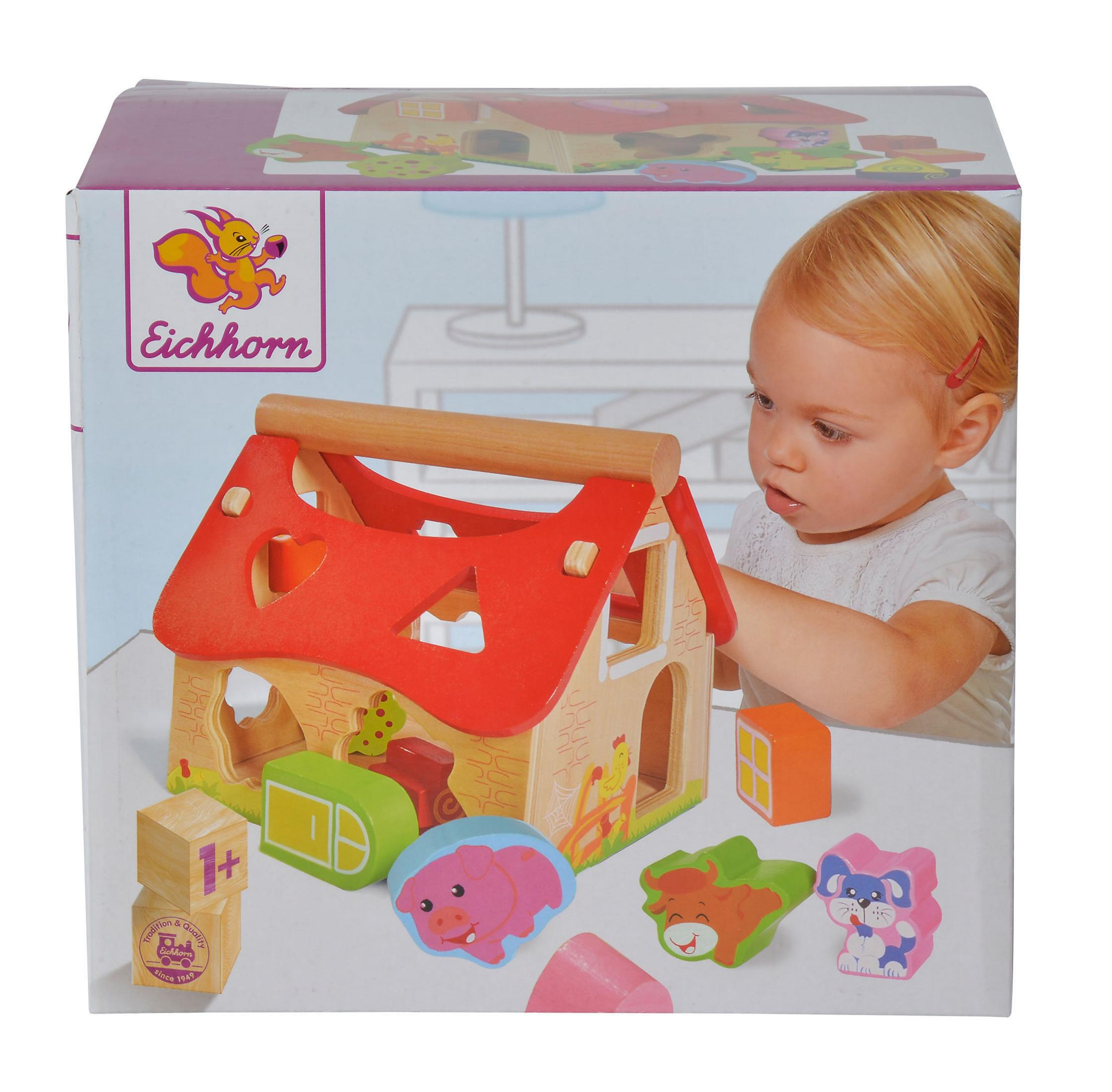 Ein Kind betrachtet ein Holzspielhaus mit Tierformen, in einer Box.