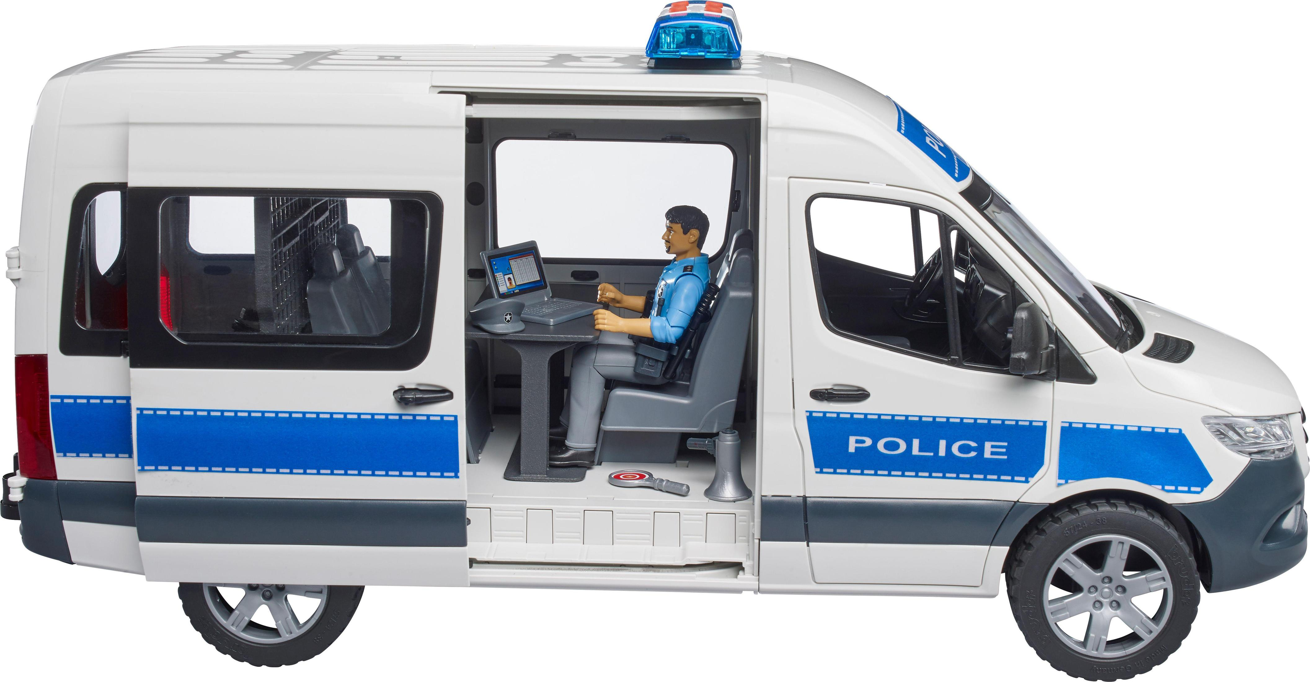 Furgon policji z otwartymi drzwiami, mężczyzna używa laptopa. Niebieskie i białe oznaczenia.