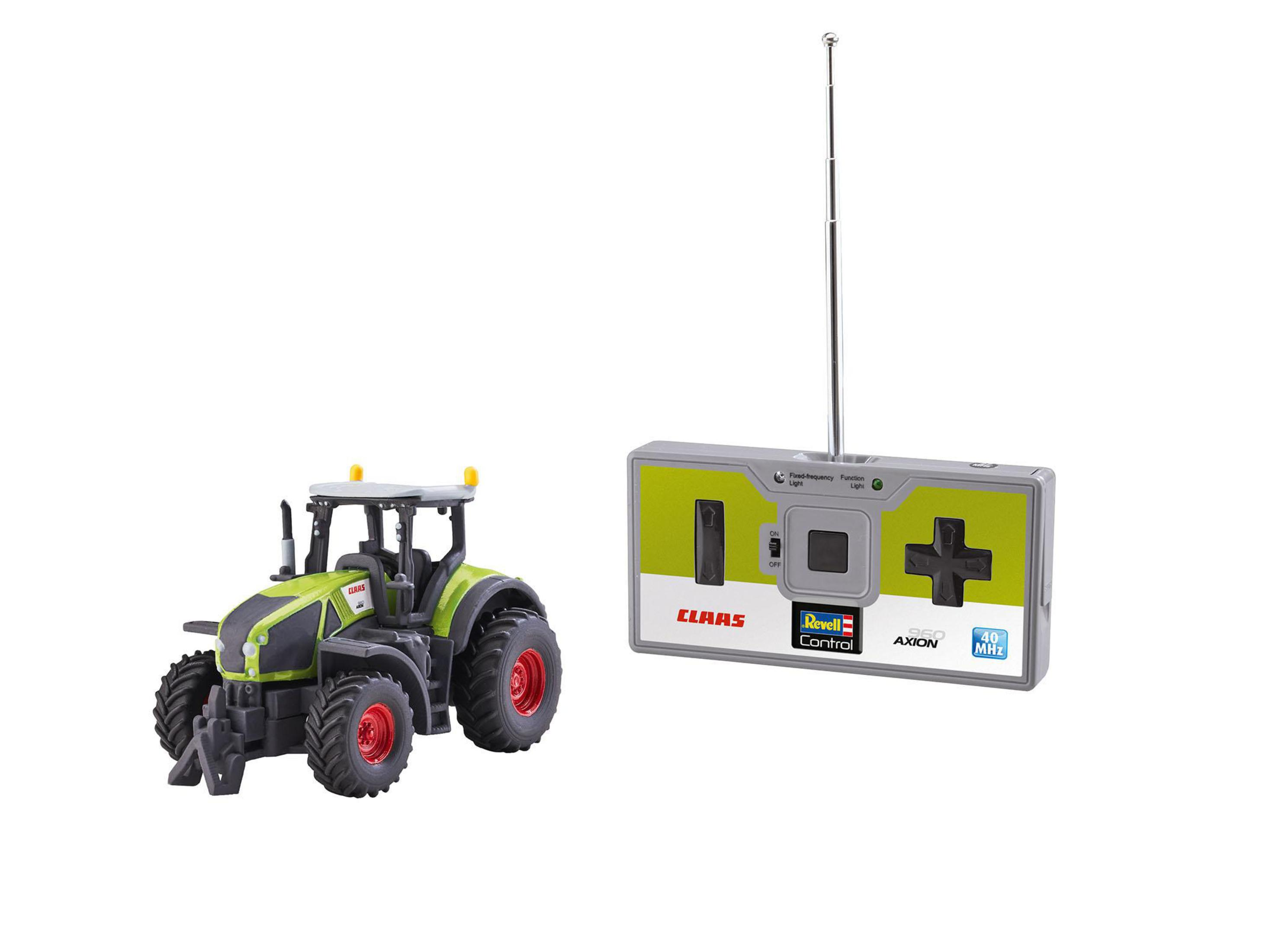 Un tractor de juguete verde y negro con un mando a distancia. El tractor está sobre una superficie blanca.