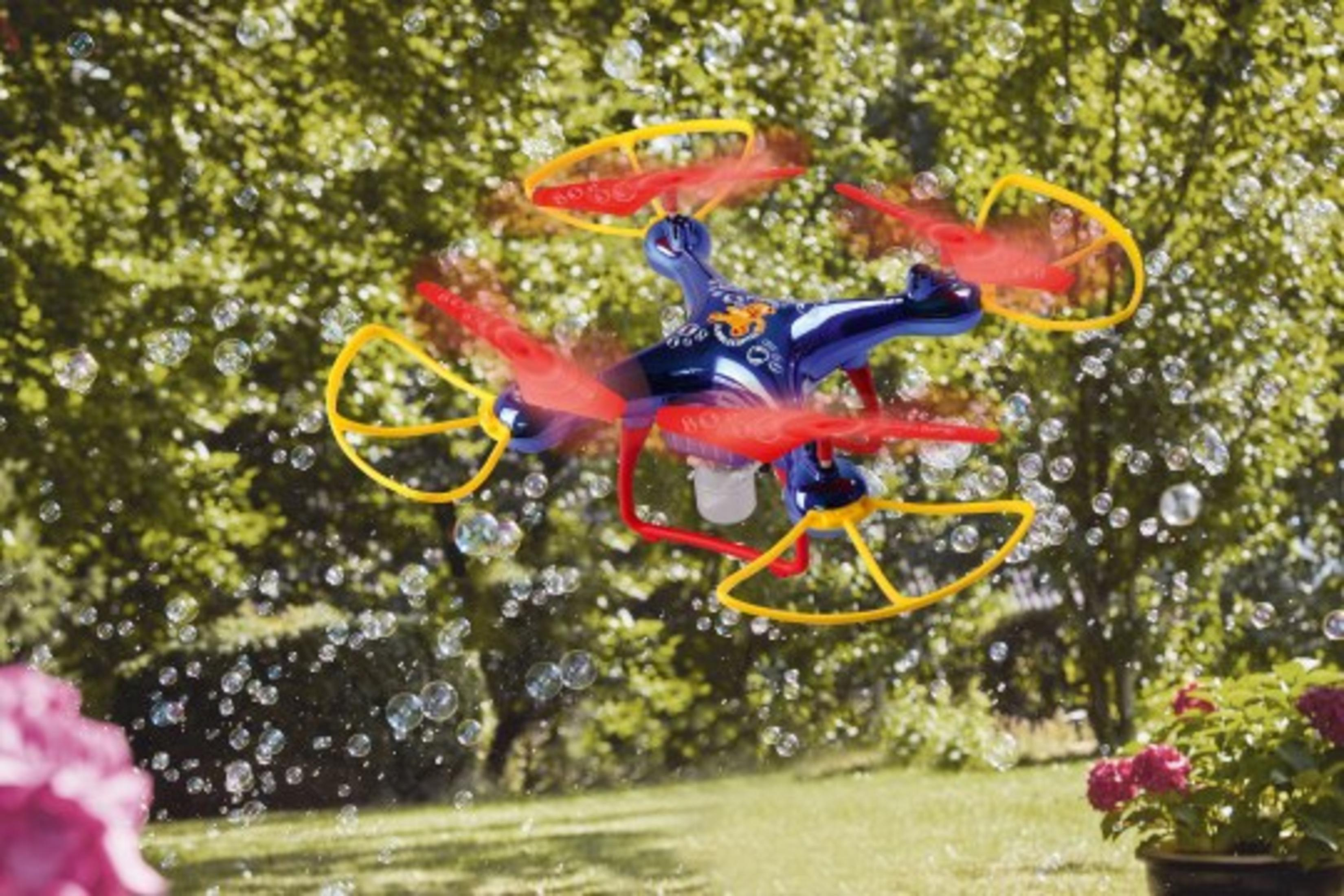 Eine blaue und rote Drohne, die inmitten von Blasen in einem Garten fliegt.
