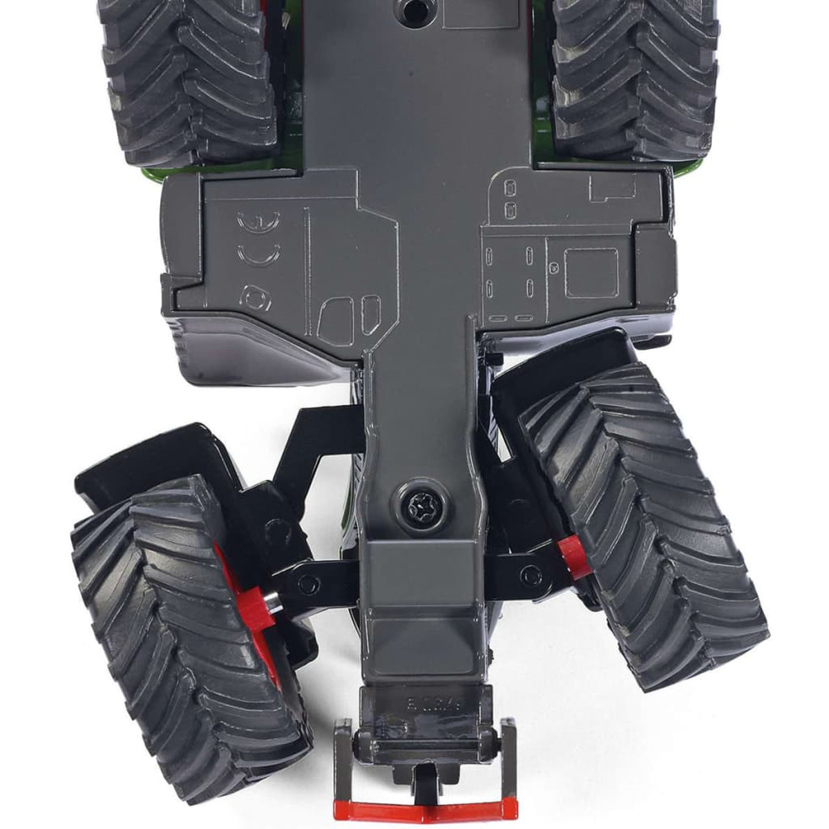 Widok od spodu zabawkowego traktora z dużymi czarnymi oponami i czerwonymi akcentami, białe tło.