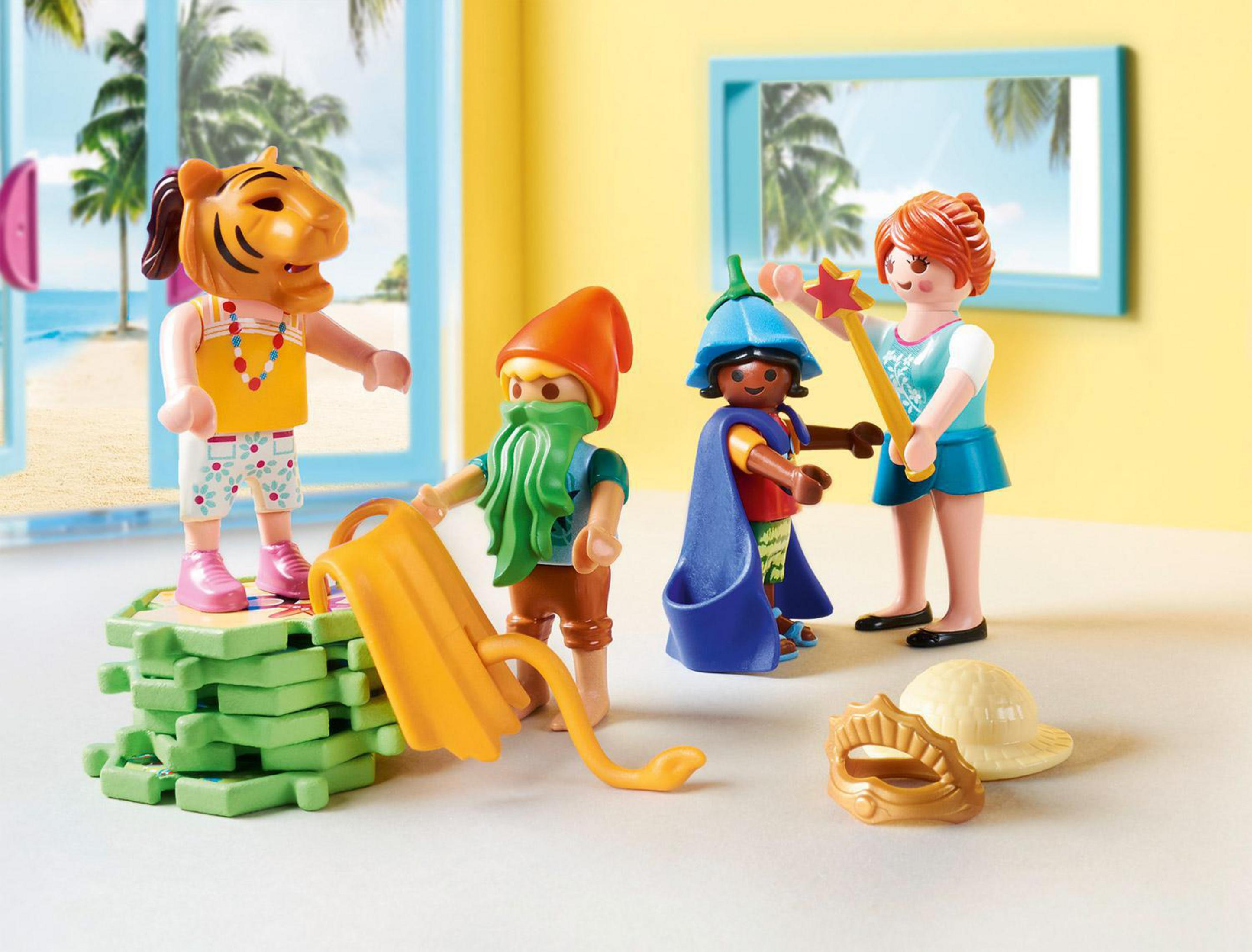 Figurki Playmobil przebrane za tygrysa, gnoma, wróżkę i kobietę, na plaży.